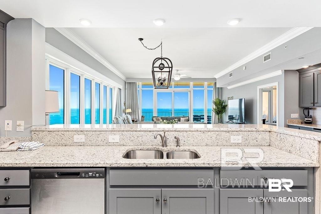 Image 2: Kitchen featuring gray cabinetry, light-toned stone countertops, and a double basin stainless steel sink