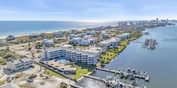 Image 2: Coastal property featuring a multi-story building, an outdoor pool, and private boat docks