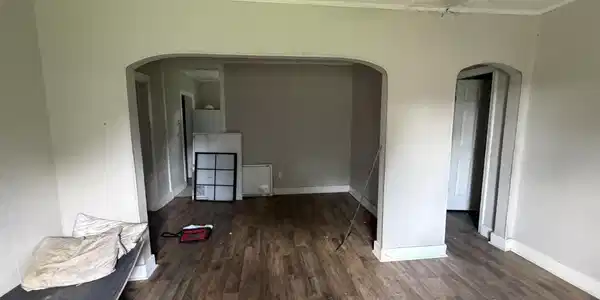 Image 4: Spacious interior featuring wood-finish flooring, light-colored walls, and crown molding