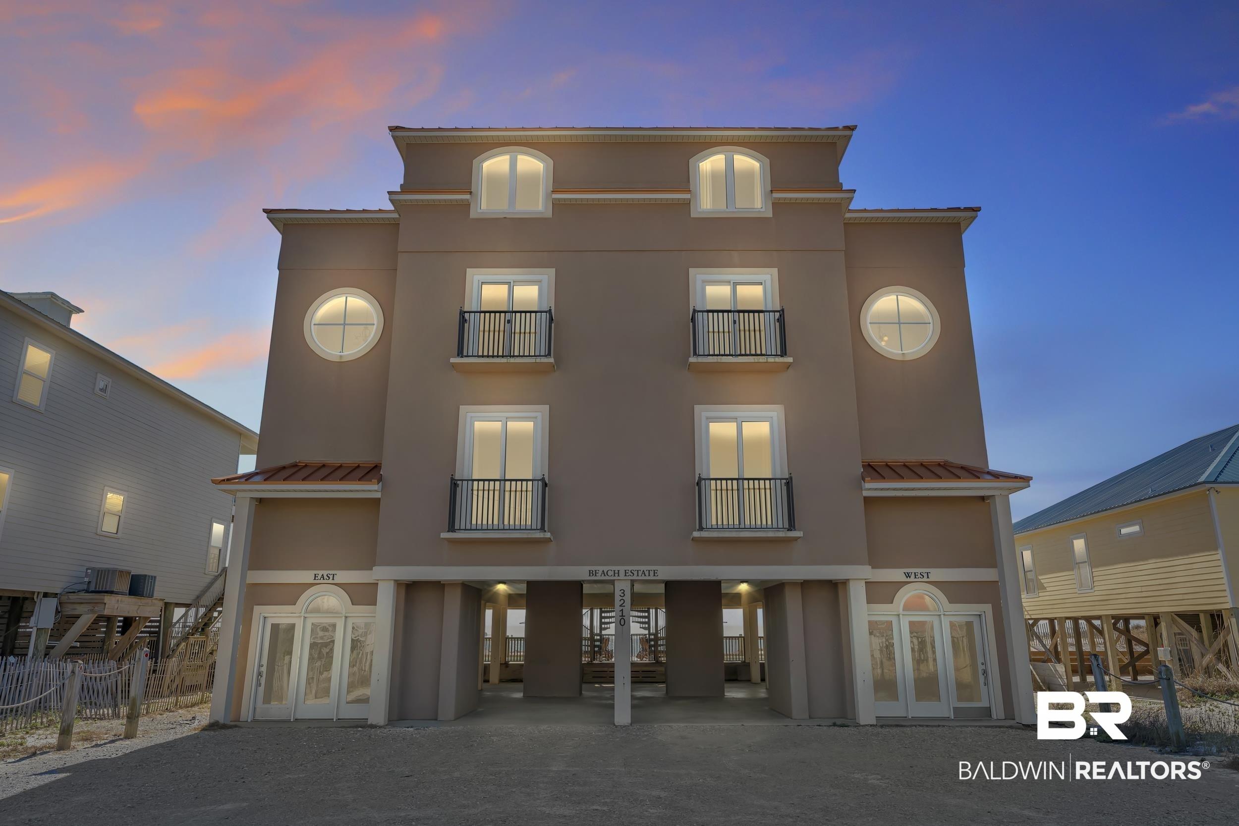 Image 2: Back of house at dusk with french doors, a balcony, and stucco siding