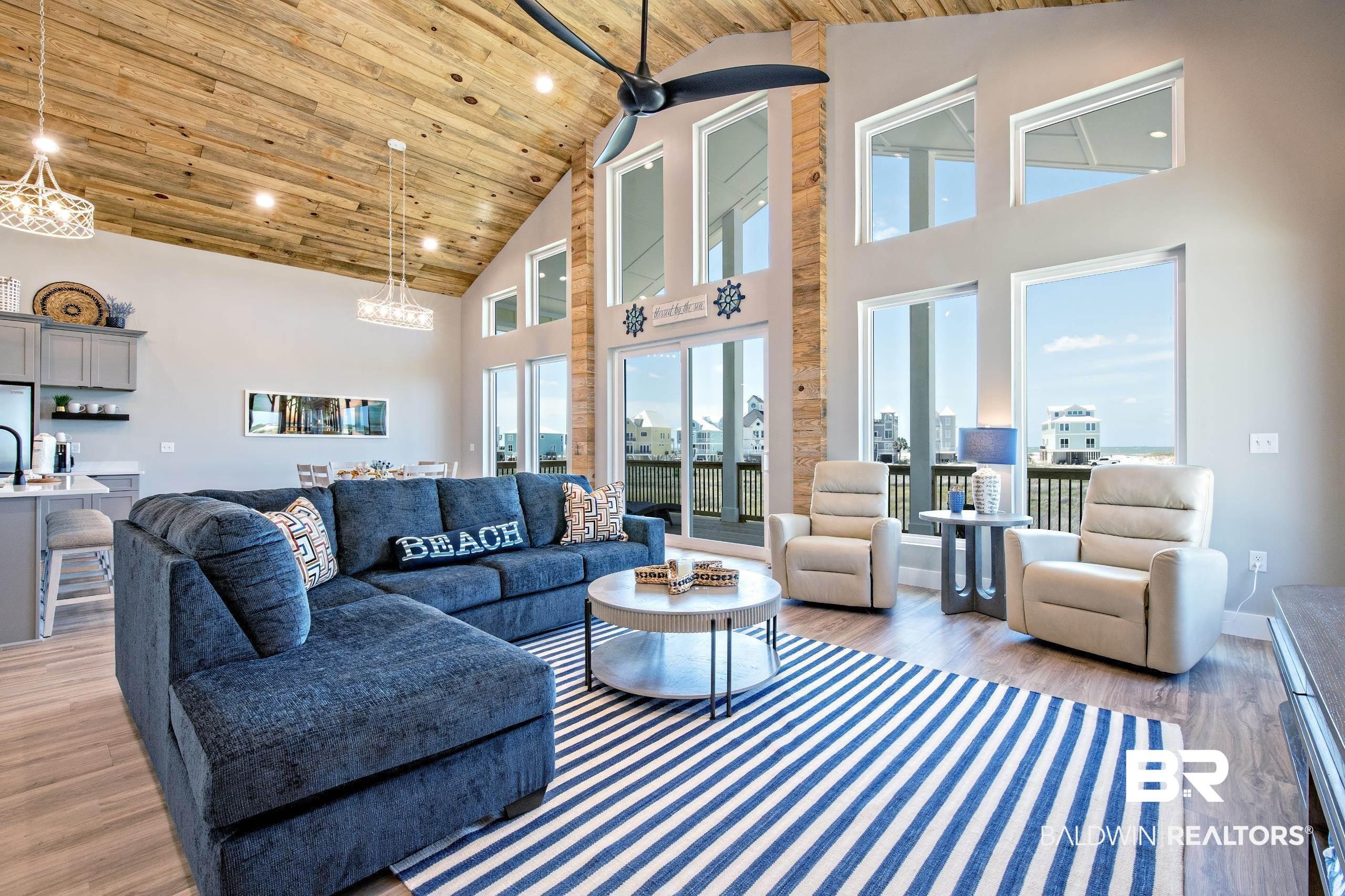 Image 2: Vaulted wood-finish ceiling complementing an open-concept living area with extensive windows