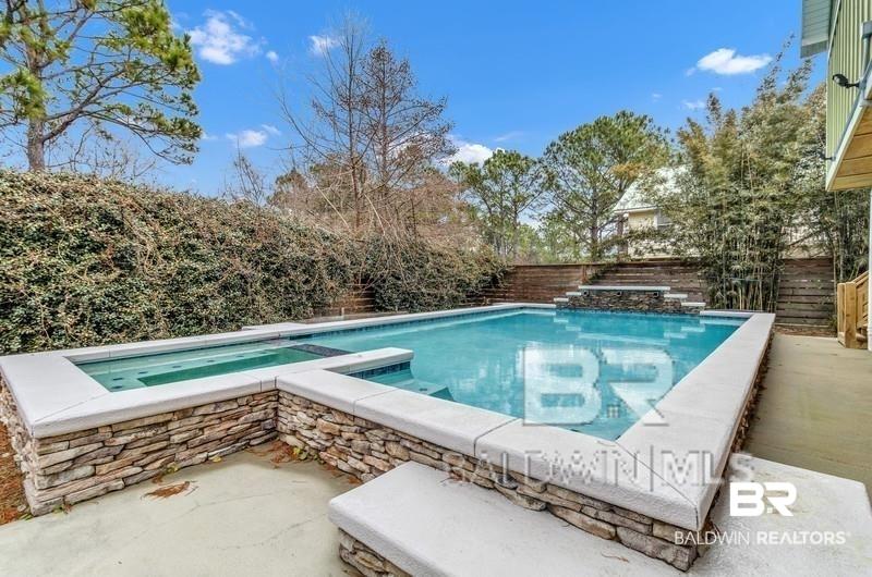Image 2: Outdoor swimming pool with integrated spa and waterfall feature, surrounded by stacked stone detailing and concrete decking