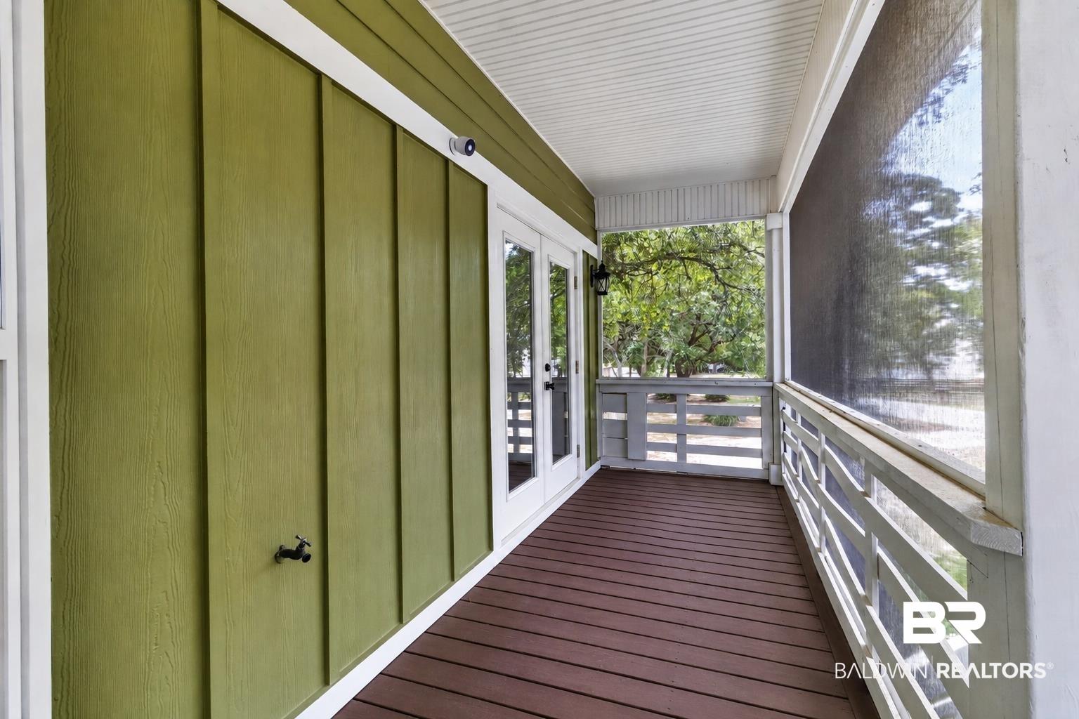 Image 4: Expansive screened porch featuring a rich brown wood-finish deck, white railing, and a board and batten wall in a warm green hue