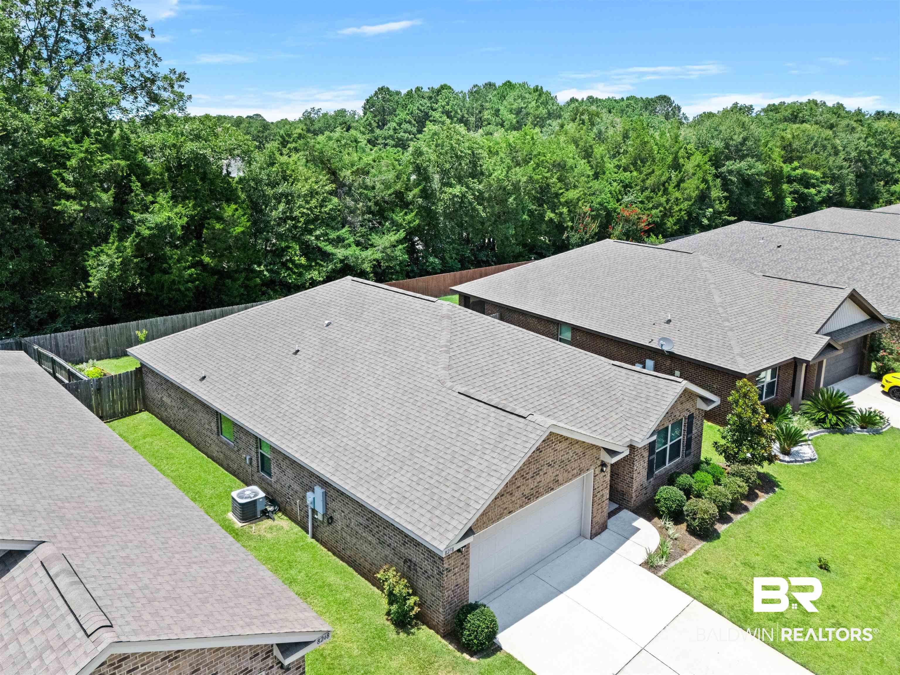Image 4: Brick exterior home featuring a two-car garage, concrete driveway, and established landscaping
