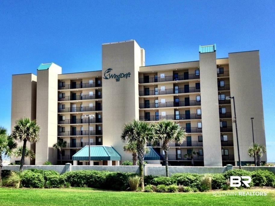 Image 1: Multi-story building featuring numerous private balconies with black railings, a central drive-through entrance with a teal roof, and palm trees