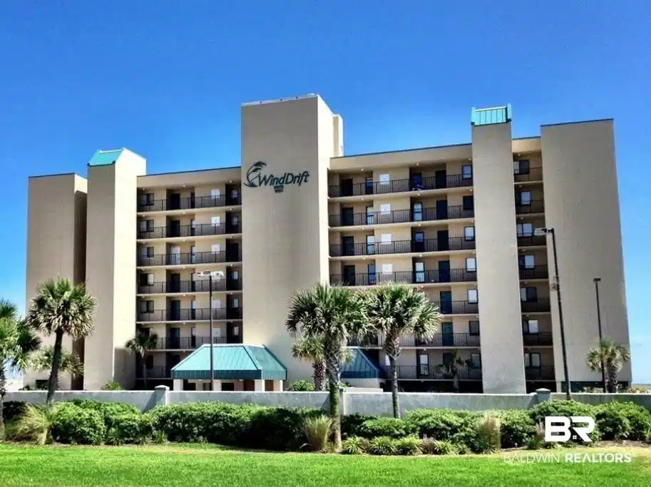 Image 1: Multi-story building featuring numerous private balconies with black railings, a central drive-through entrance with a teal roof, and palm trees