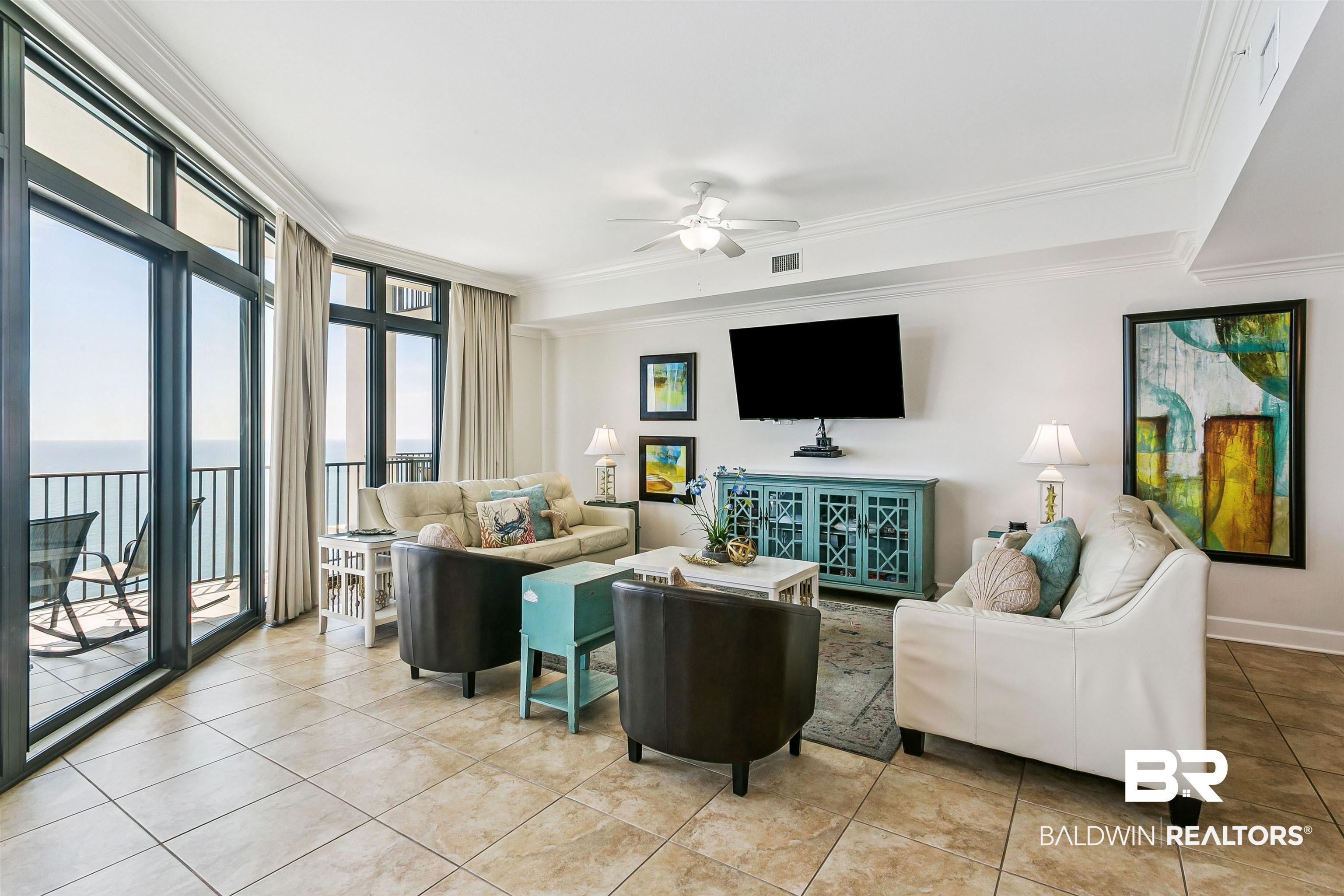 Image 4: Spacious living area featuring large format tile flooring, crown molding, and a ceiling fan