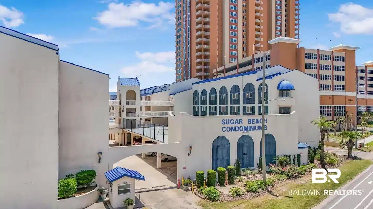 Image 1: White stucco exterior featuring blue architectural accents, arched entryways, and a prominent building sign