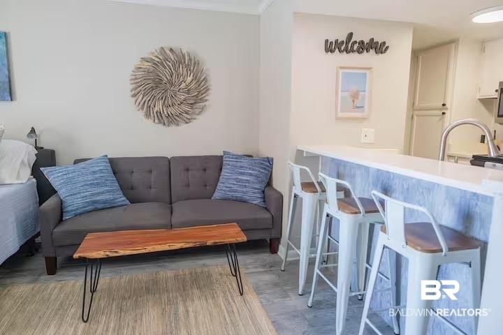 Image 4: Open-concept living space featuring a breakfast bar with seating for three, a stainless steel sink with gooseneck faucet, and light-toned flooring