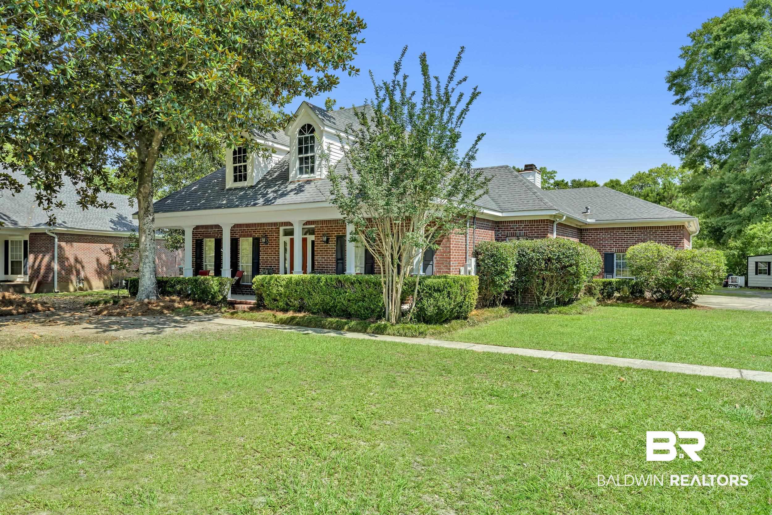 Image 2: Brick exterior with a covered front porch, white columns, and a dormer window
