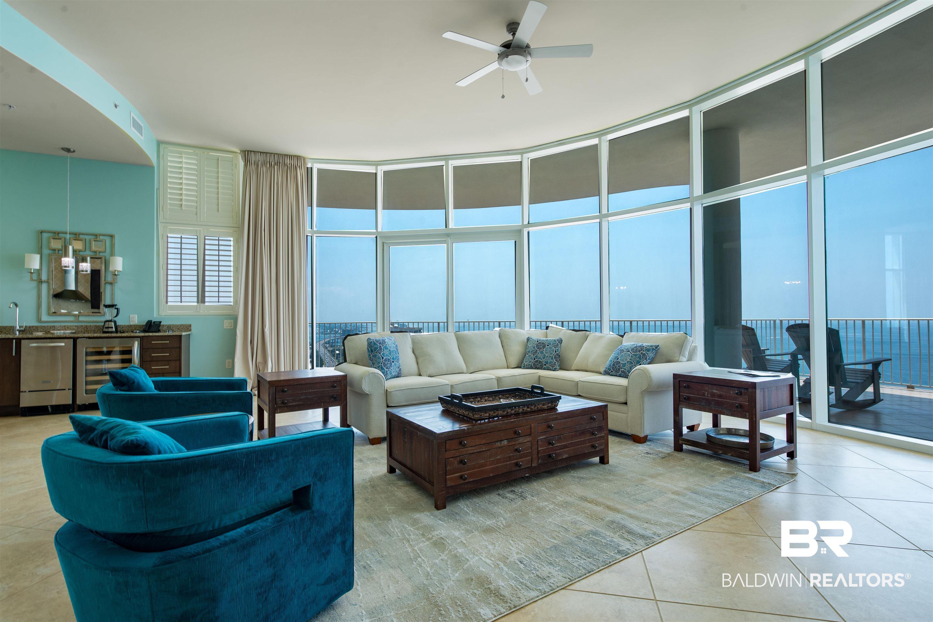 Image 2: Living room featuring expansive windows, light tile patterned floors, wine cooler, and ceiling fan