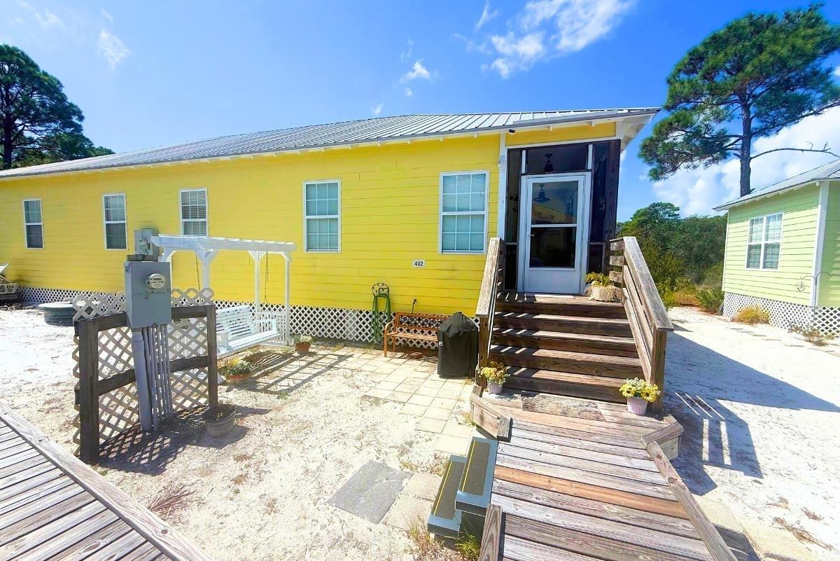 Image 2: Rear view of property featuring a metal roof and a patio area