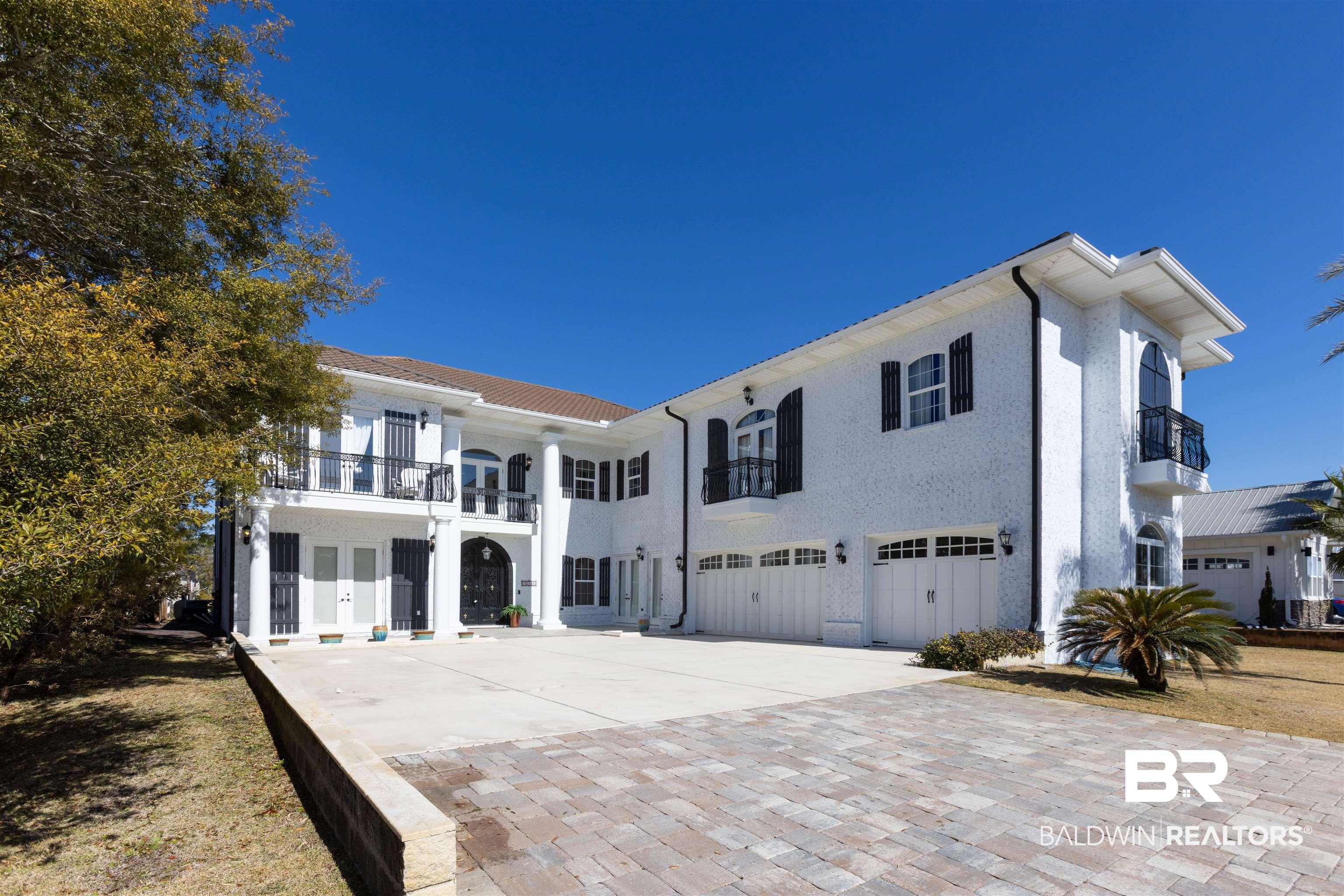 Image 1: View of front of property with a balcony, an attached garage, french doors, and driveway