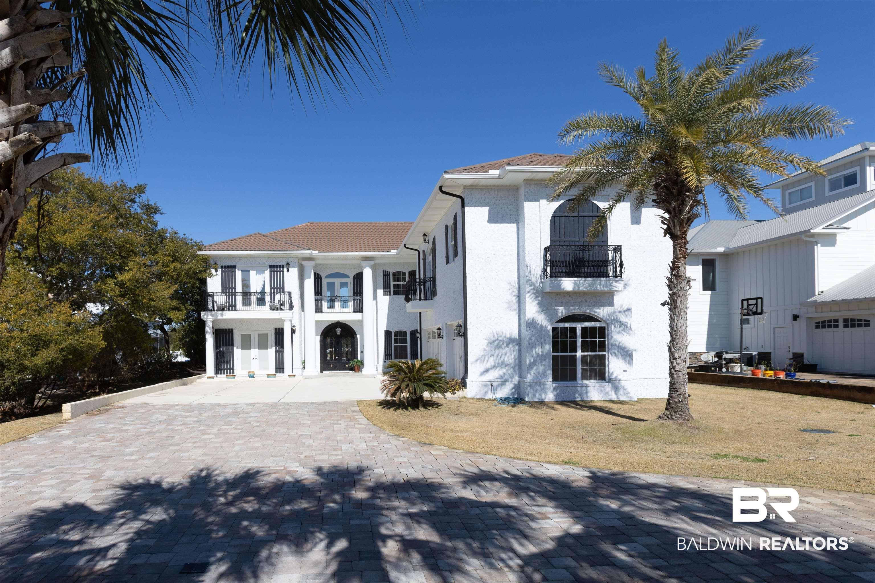 Image 2: View of front of home featuring a balcony, decorative driveway, and stucco siding