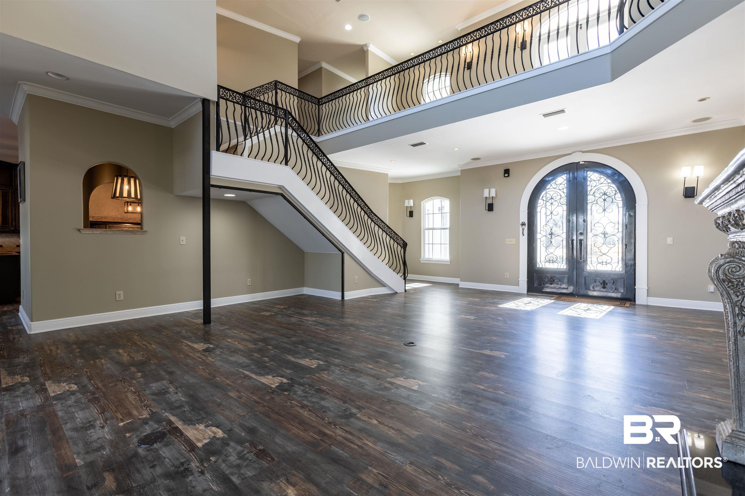 Image 3: Foyer entrance with french doors, a high ceiling, dark wood finished floors, ornamental molding, and arched walkways