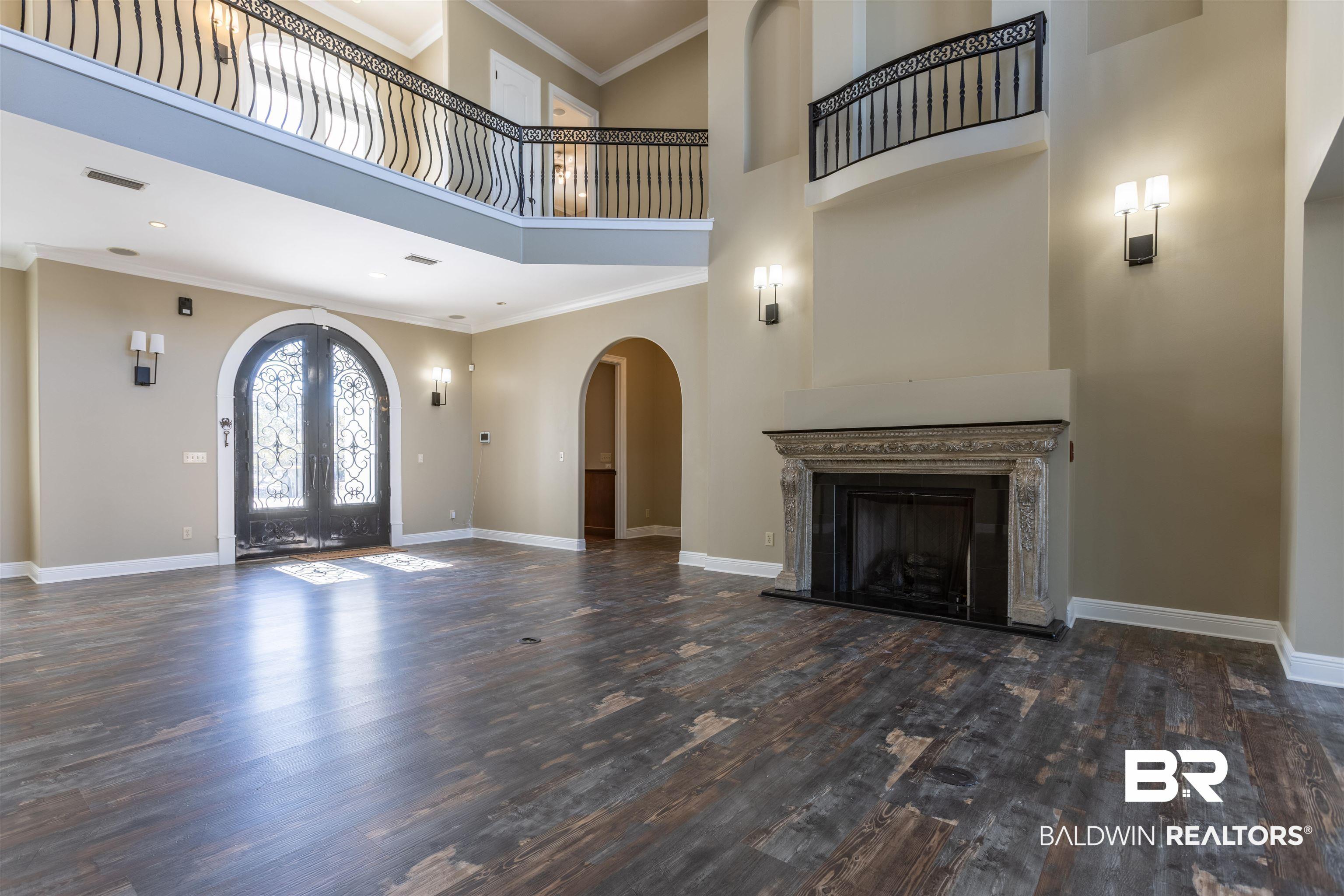 Image 4: Foyer entrance featuring ornamental molding, a high ceiling, a fireplace with raised hearth, french doors, and dark wood-type flooring