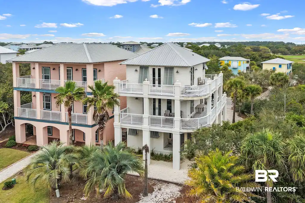 Image 1: Elevated coastal residence featuring multiple expansive balconies with white railings, a light-colored exterior, and a metal roof