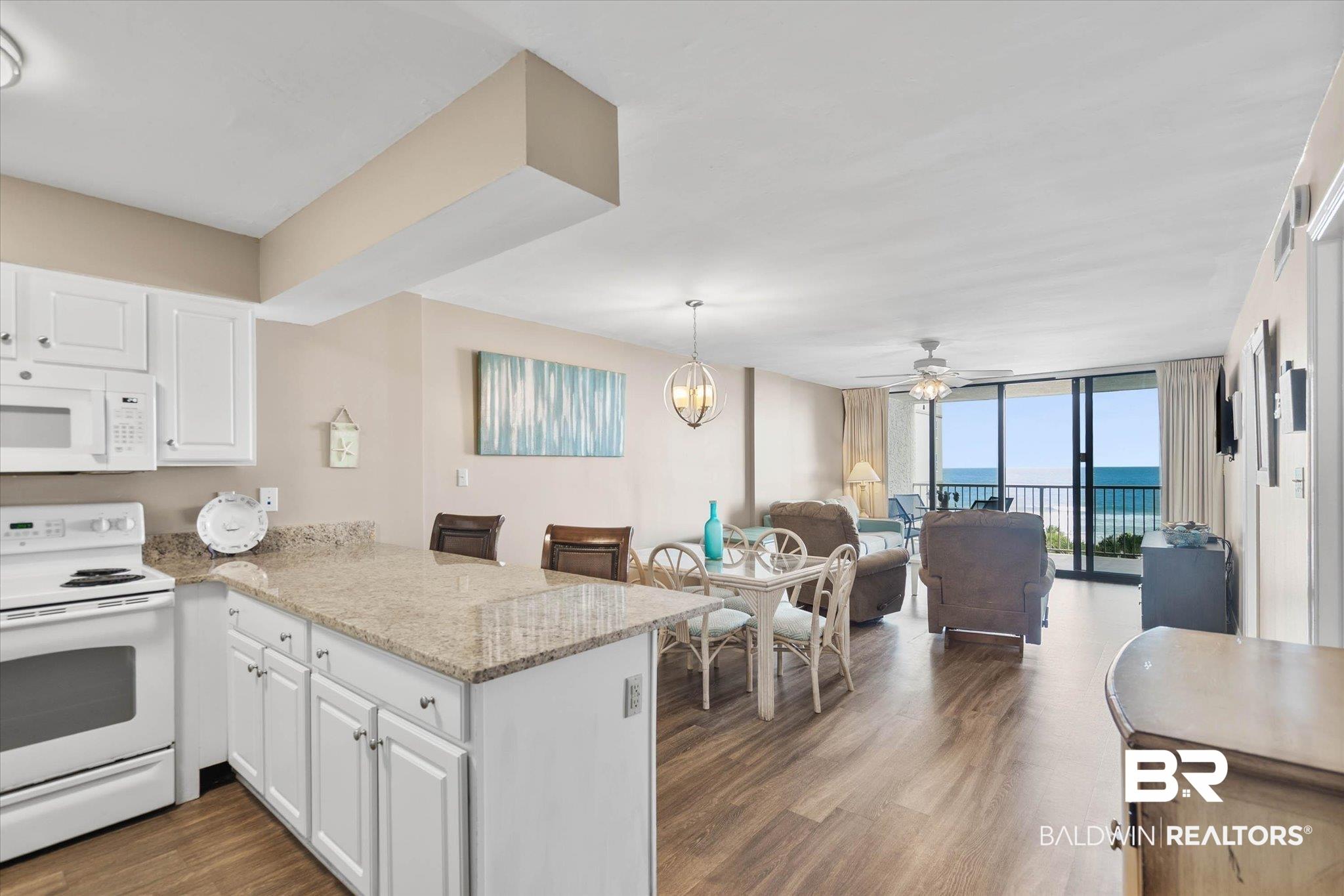 Image 2: Kitchen featuring white cabinetry, granite-finish countertops, and an integrated breakfast bar