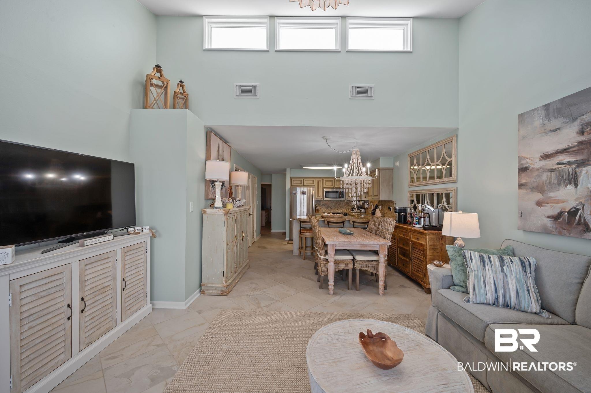 Image 4: Living room with a chandelier, light marble finish floors, plenty of natural light, and a high ceiling