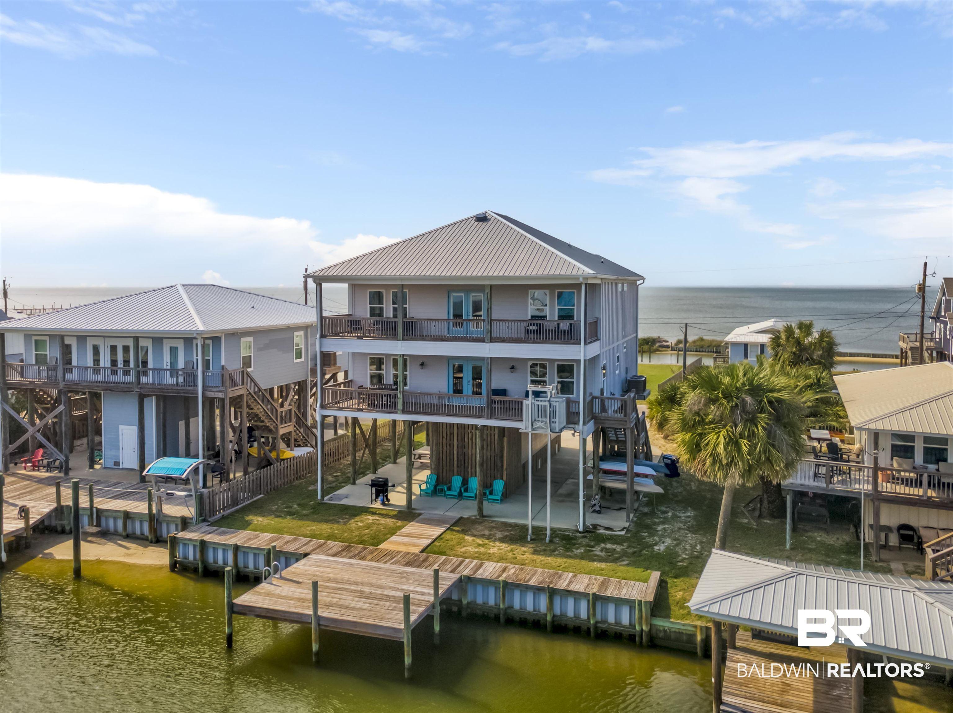 Image 2: Elevated coastal residence featuring a metal roof, multiple covered balconies, a private boat dock, and direct water frontage