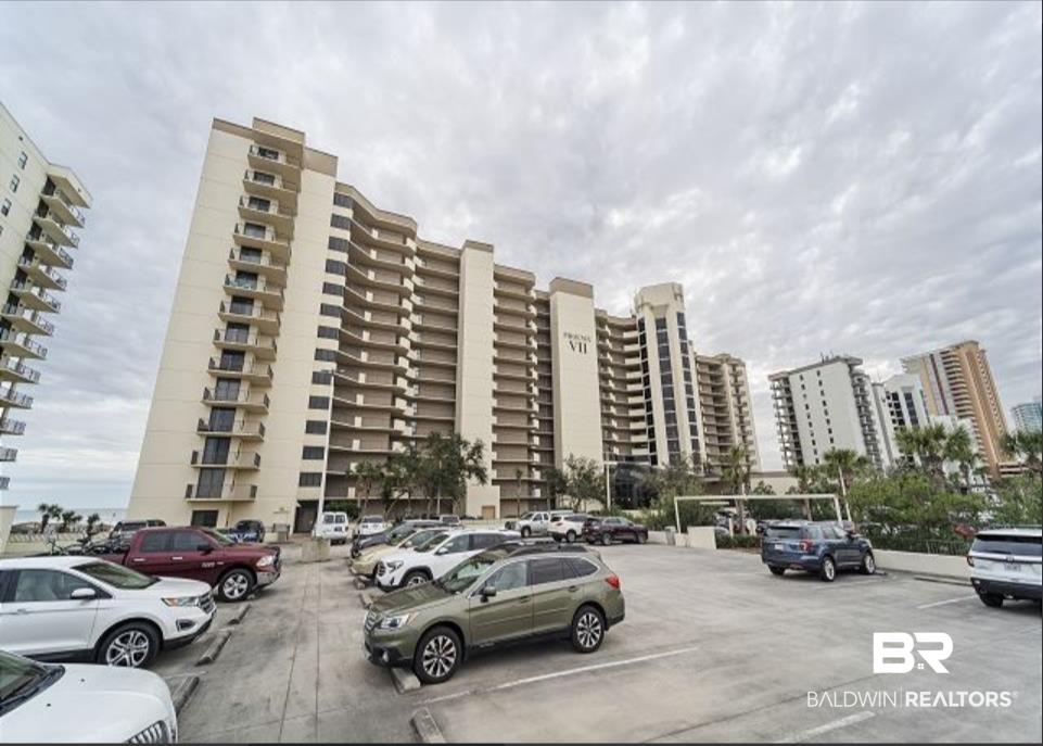 Image 3: Multi-story condominium building featuring numerous private balconies, a light-toned exterior, and an integrated parking area