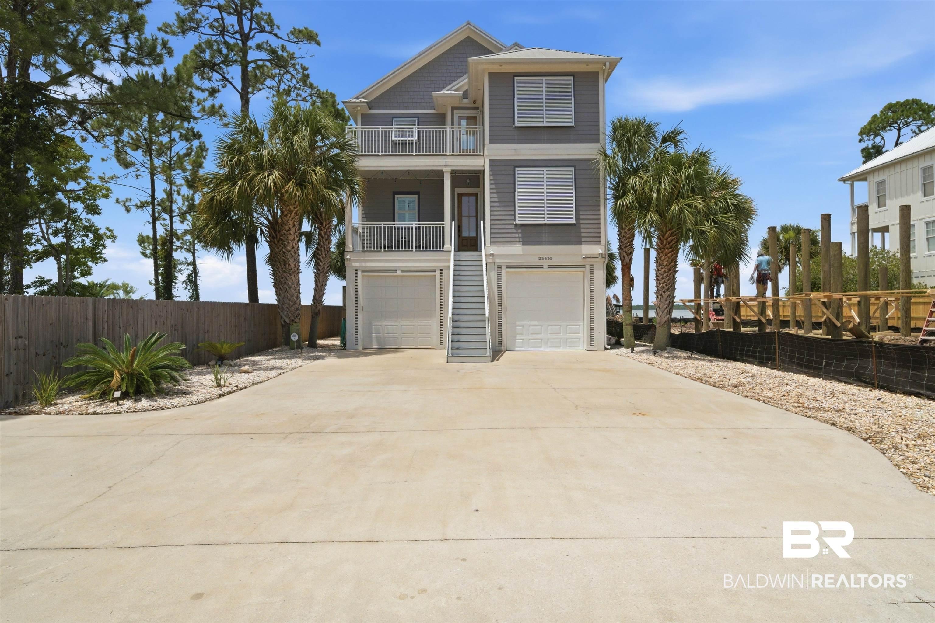 Image 1: Three-story coastal-style residence featuring a gray exterior with white trim