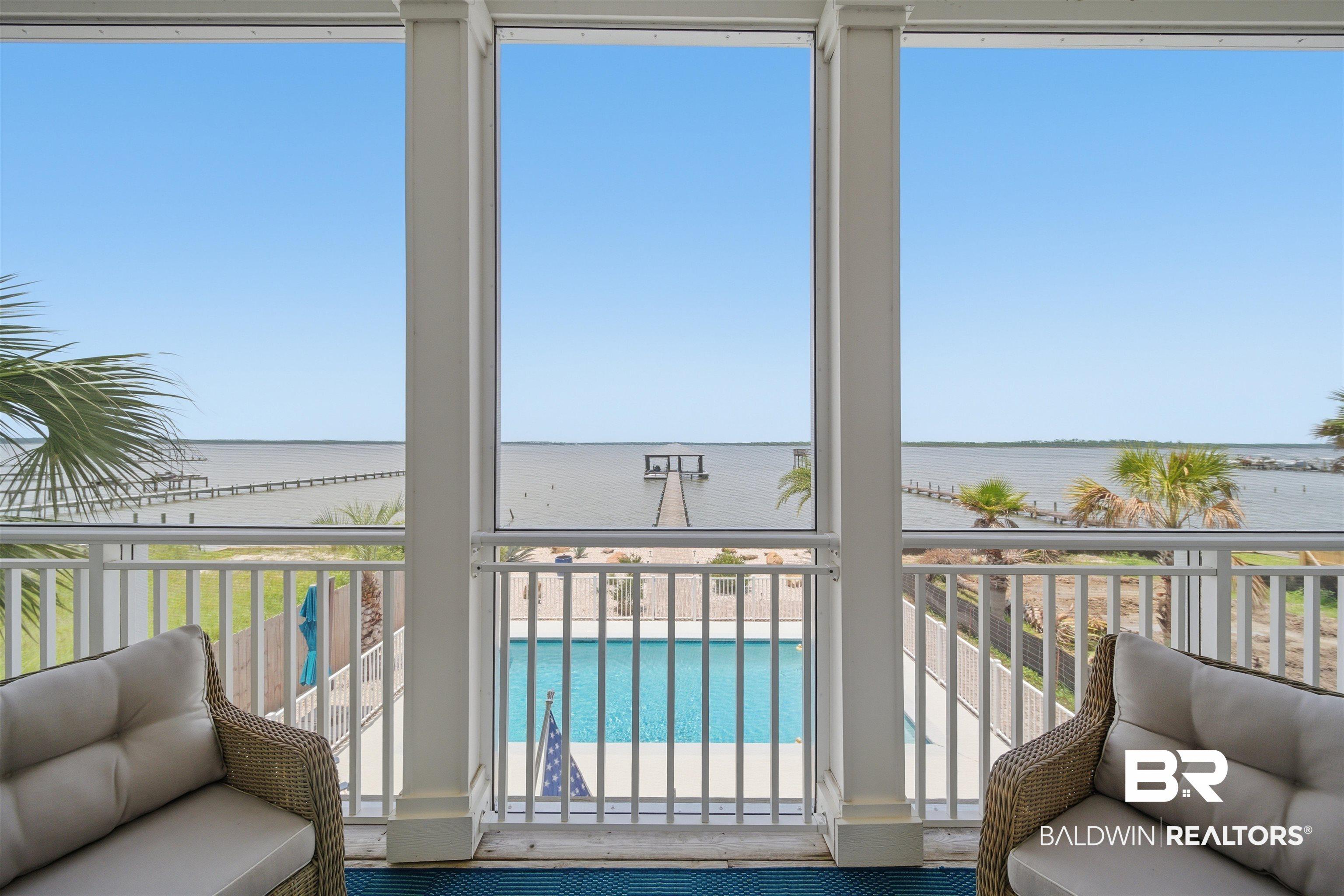 Image 2: Expansive waterfront vista from a covered patio featuring a private swimming pool and a pier extending into the water