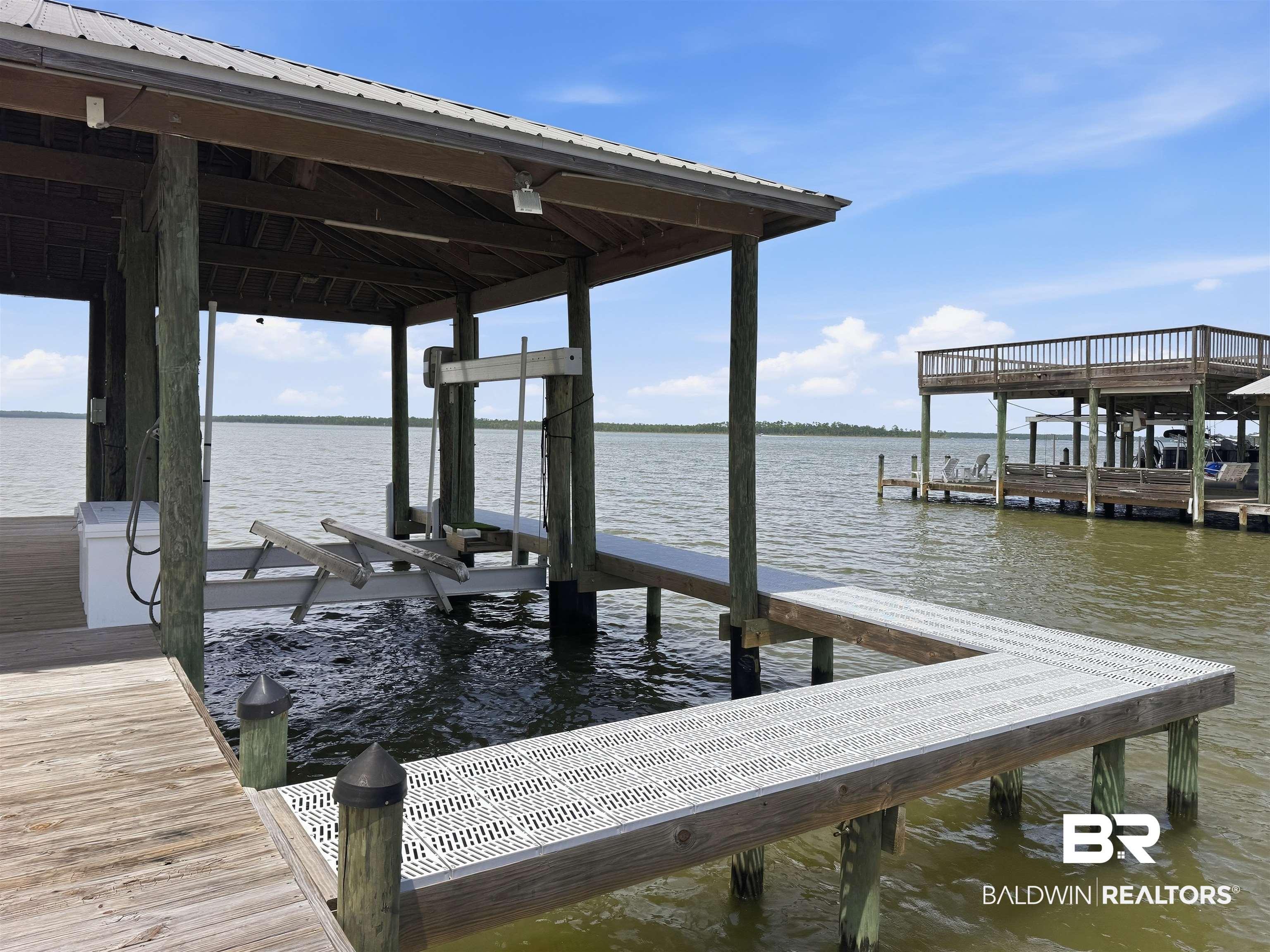 Image 4: Covered boat dock featuring a metal roof, boat lift, and composite decking