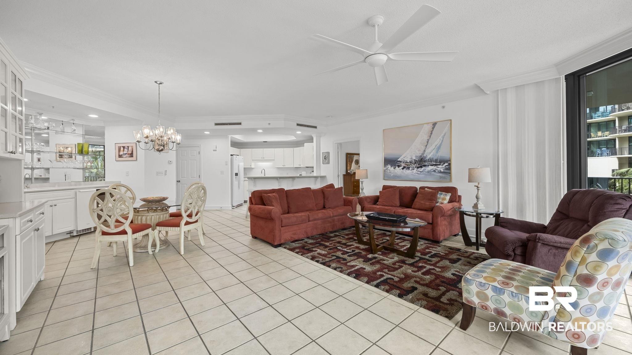 Image 2: Open-concept living area featuring tile flooring, a ceiling fan, and a built-in wet bar with glass-front cabinetry