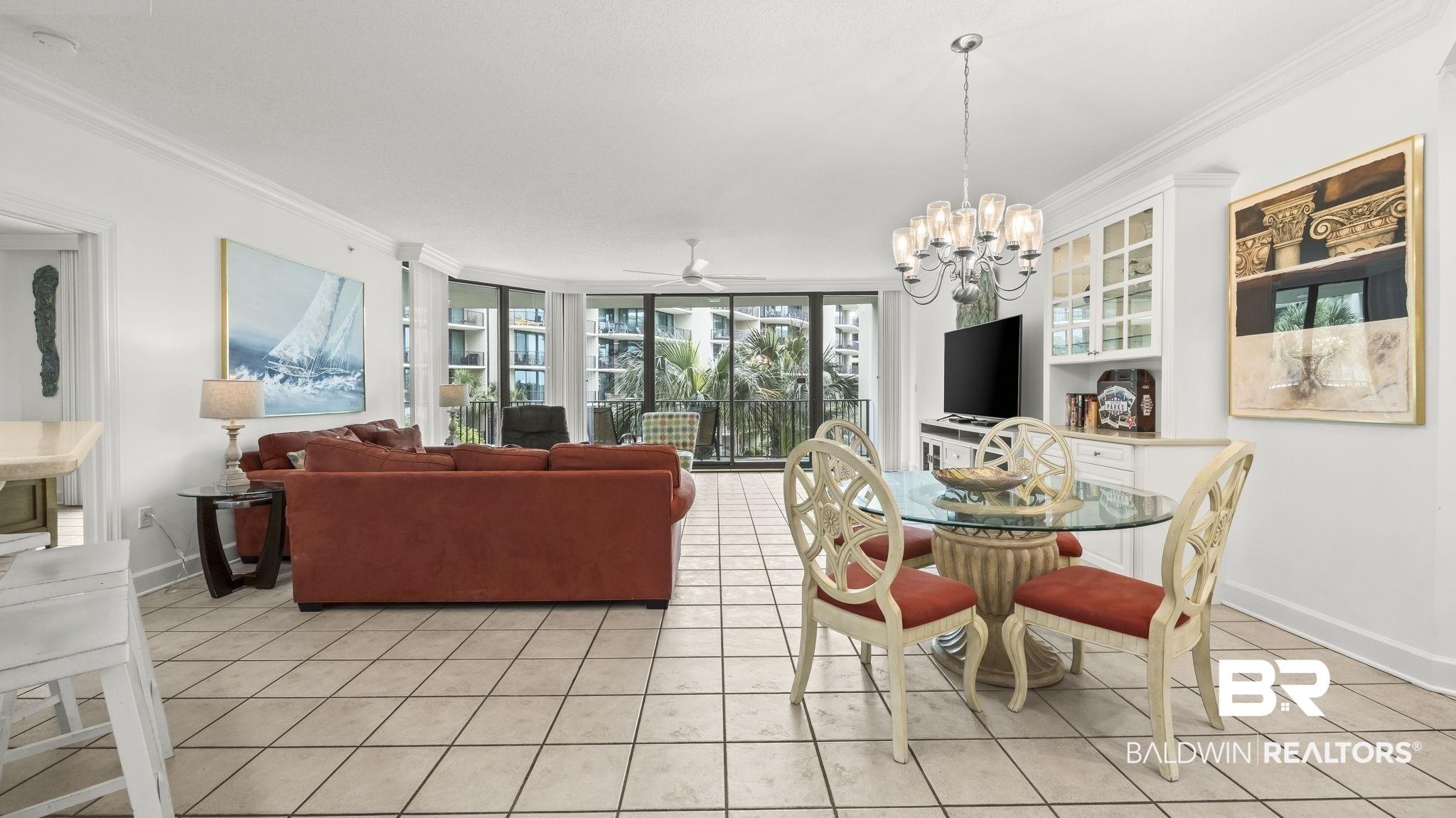 Image 3: Open-concept living space with tile flooring, a built-in display cabinet, and a multi-pane glass door opening to an exterior balcony