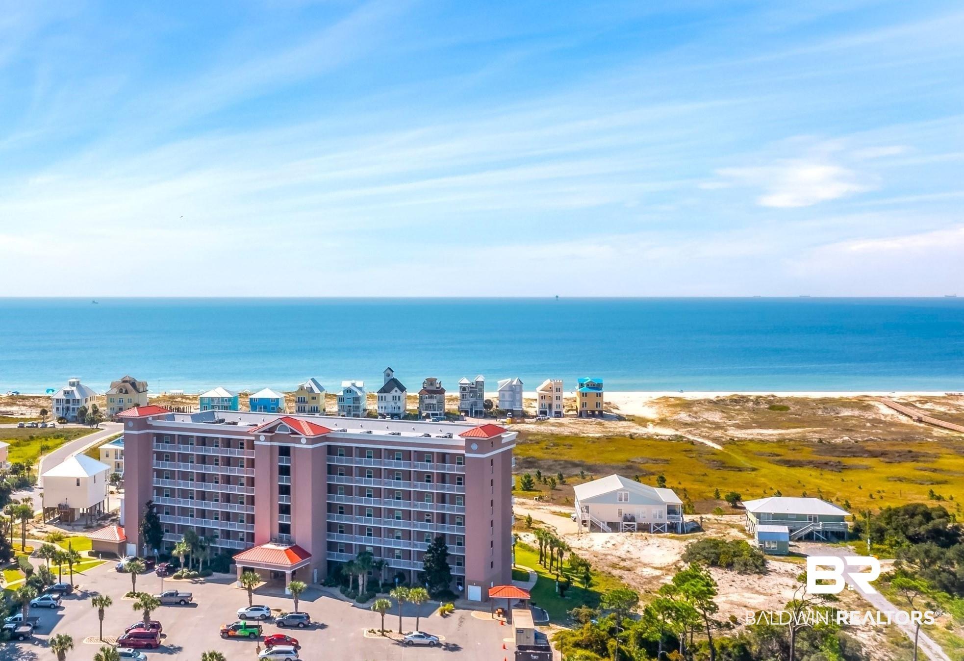 Image 2: Multi-story condominium building featuring a red roof and extensive balcony space