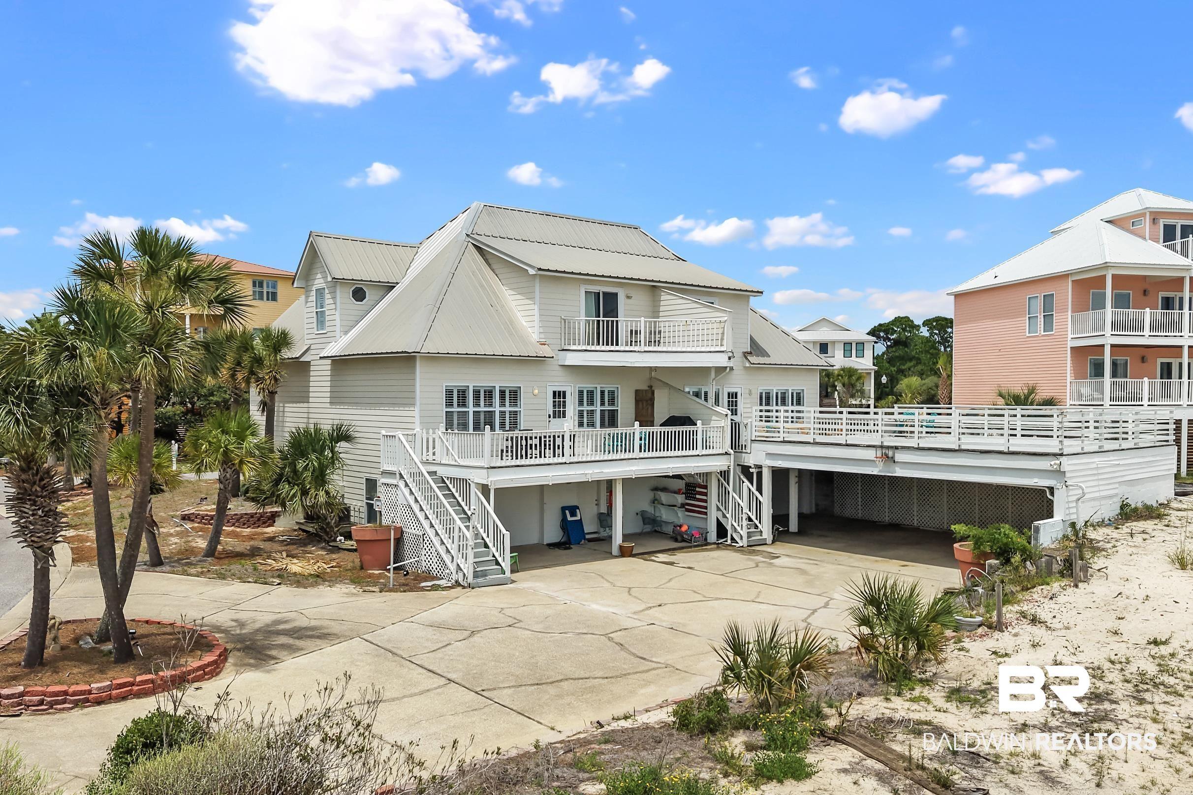Image 2: Multi-level coastal residence with white siding and a metal roof