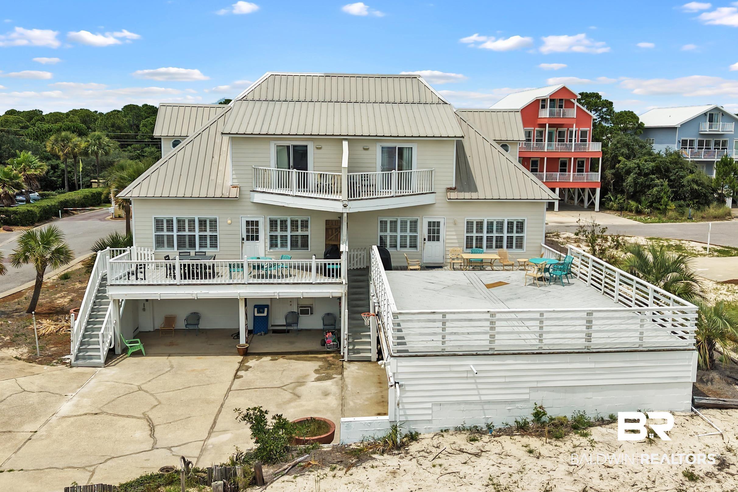 Image 3: Multi-level residence featuring a metal roof, multiple balconies, and an expansive ground-level deck with white railing