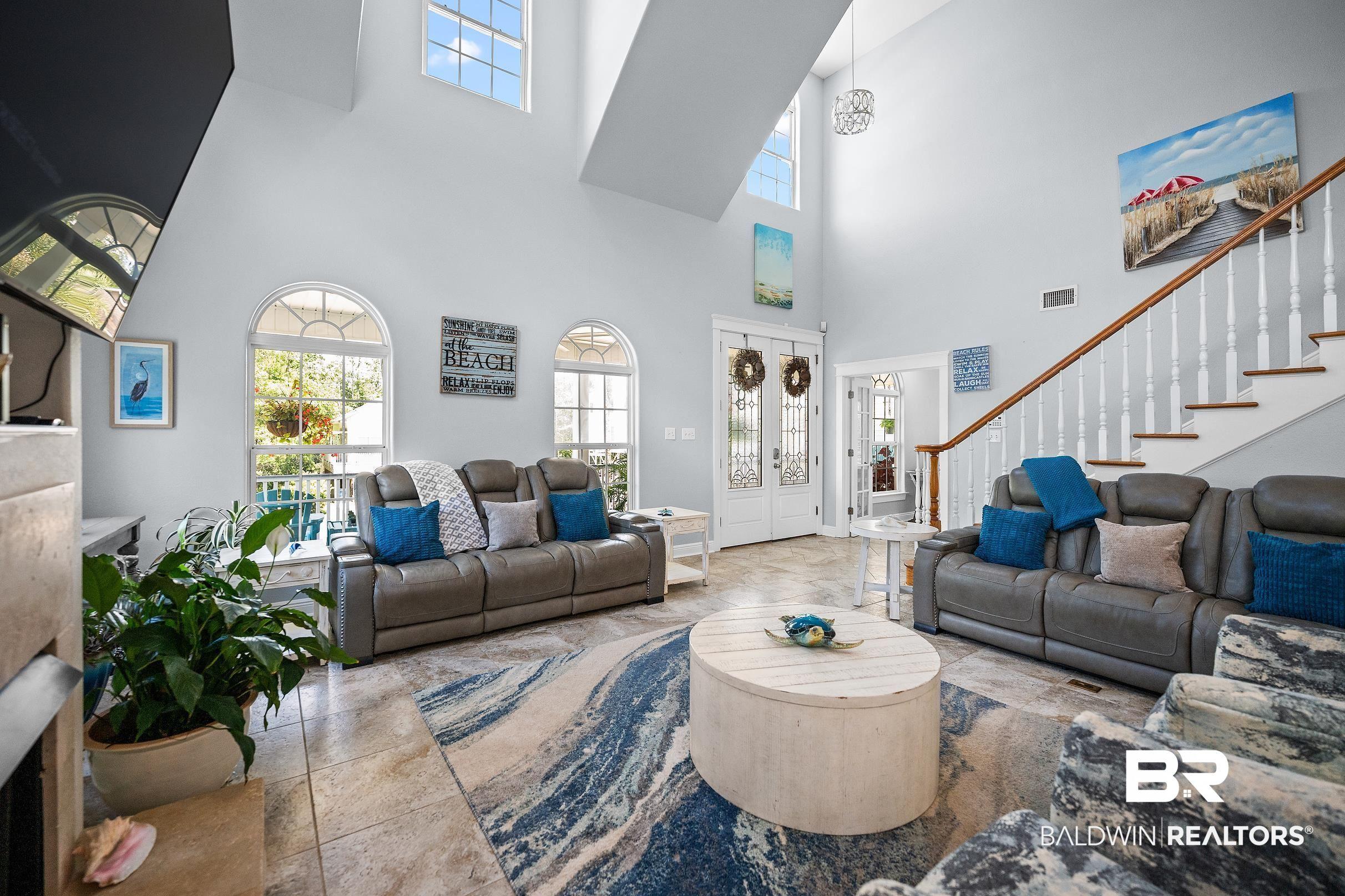 Image 2: Vaulted great room featuring high ceilings with upper transom windows, arched windows, and tile flooring