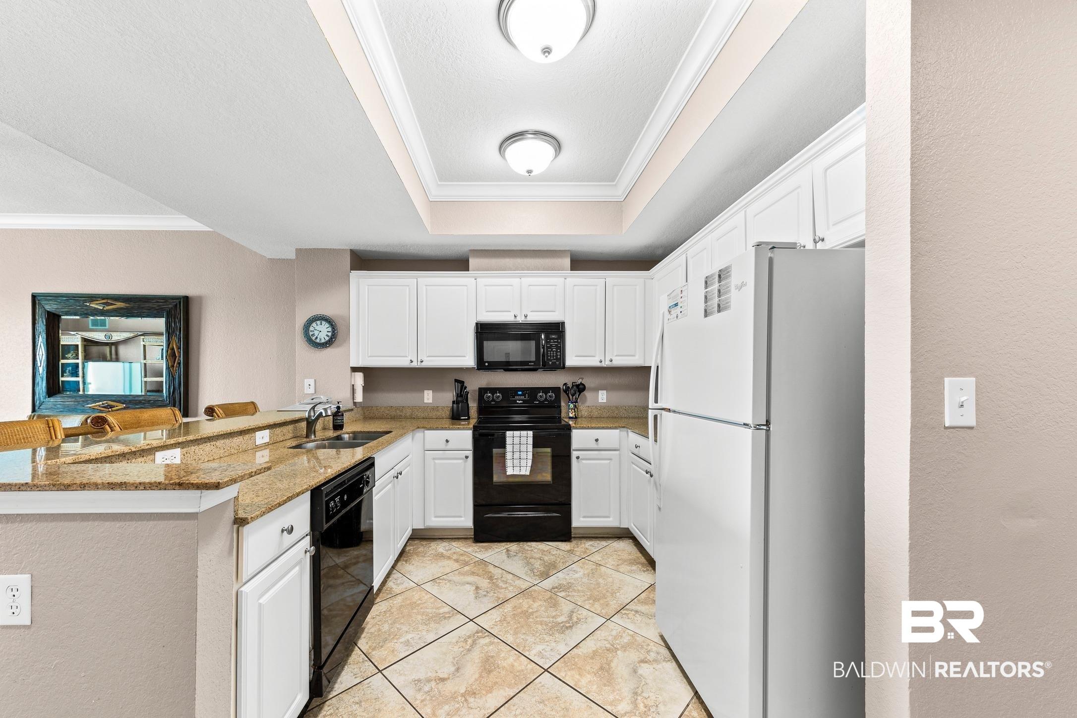 Image 2: Kitchen featuring white cabinetry, granite countertops, stainless steel sink, black appliances, and diagonal tile flooring