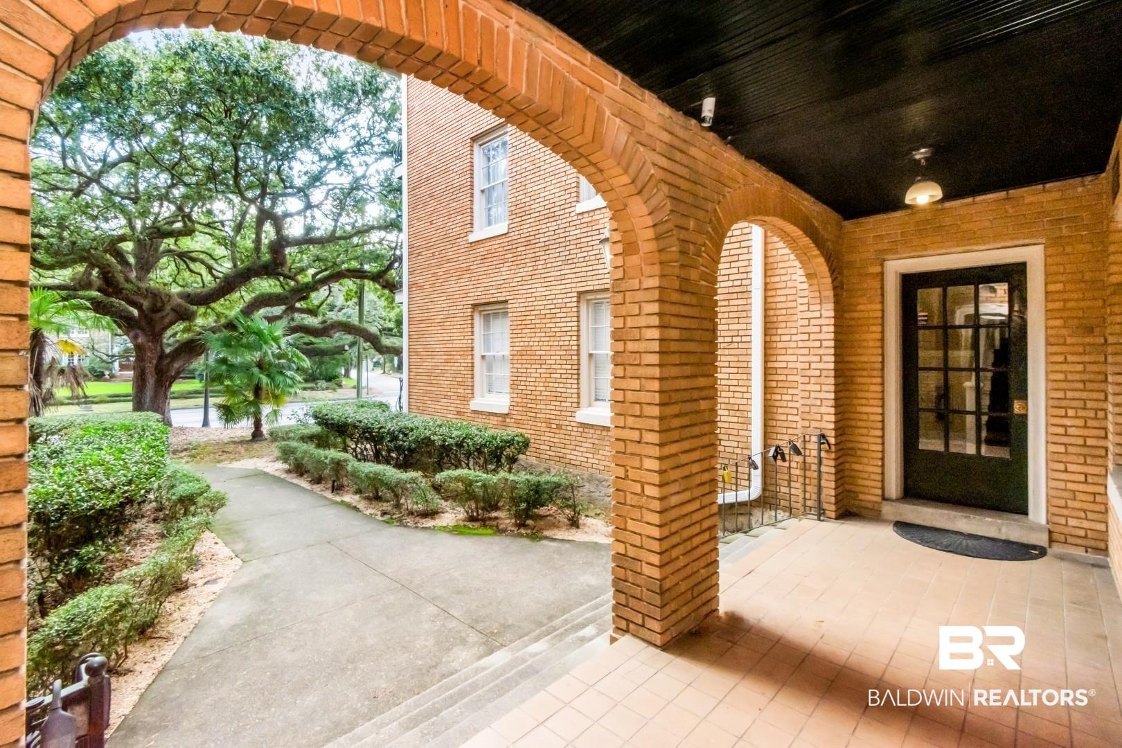 Image 3: View of exterior entry featuring brick siding and a patio