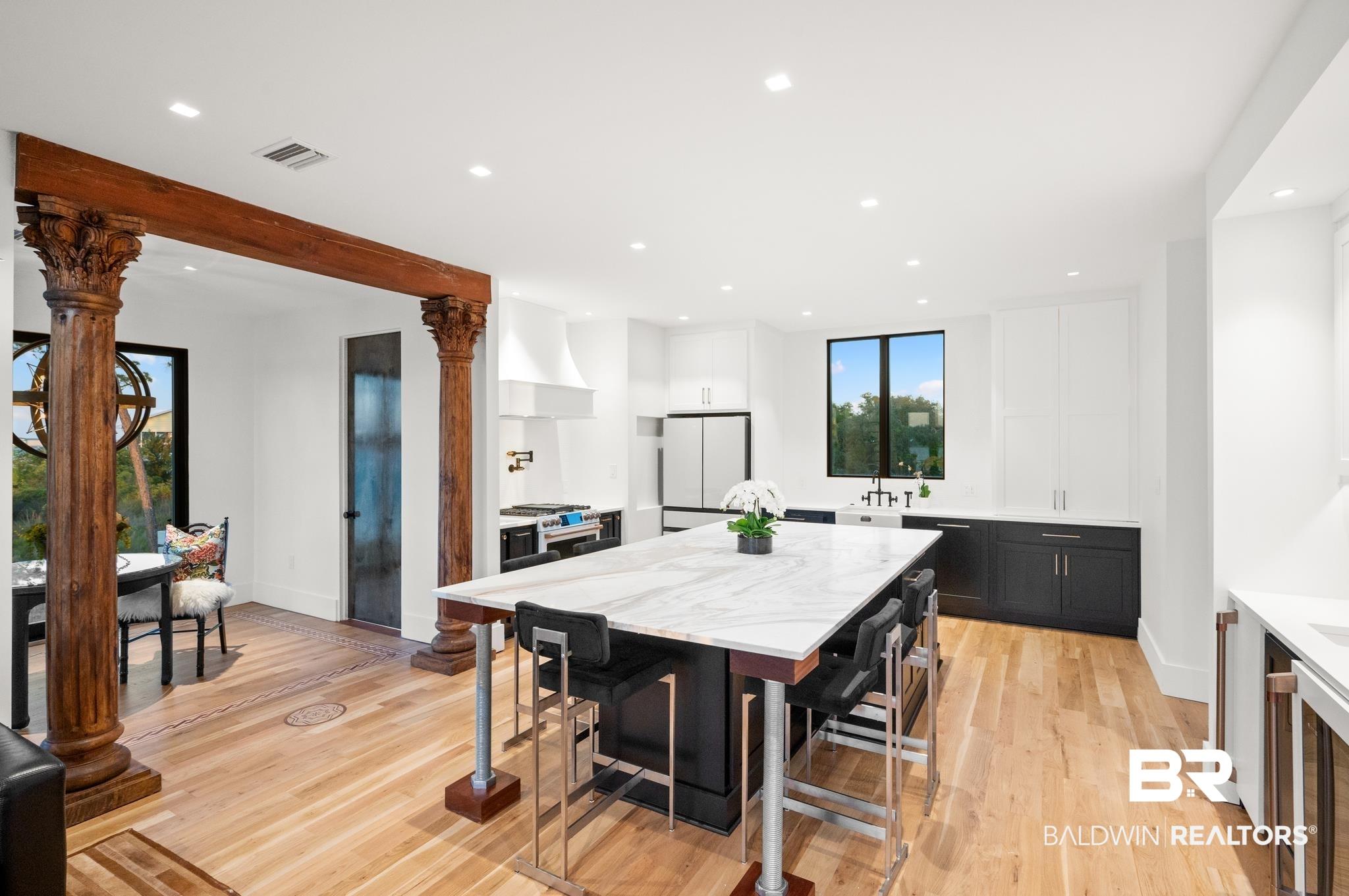Image 3: Gourmet kitchen featuring a large island with a substantial stone countertop, recessed lighting, and wood-finish flooring