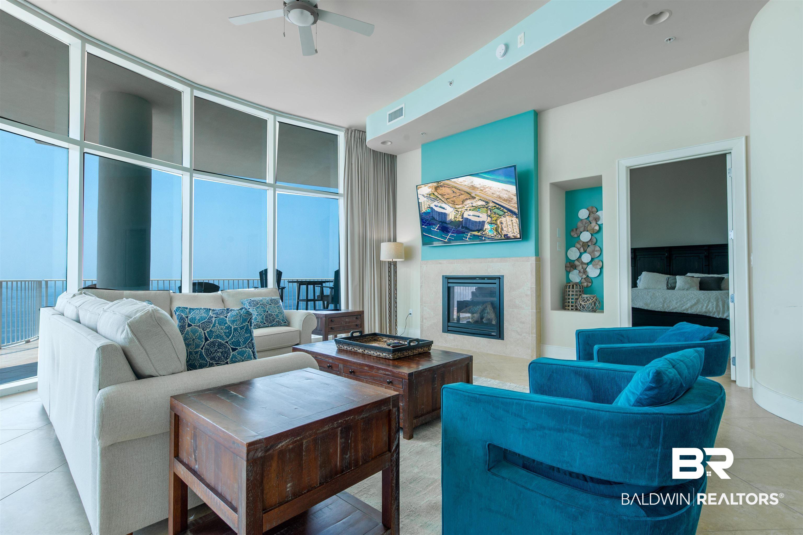Image 3: Tiled living room with expansive windows, a tile fireplace, and ceiling fan