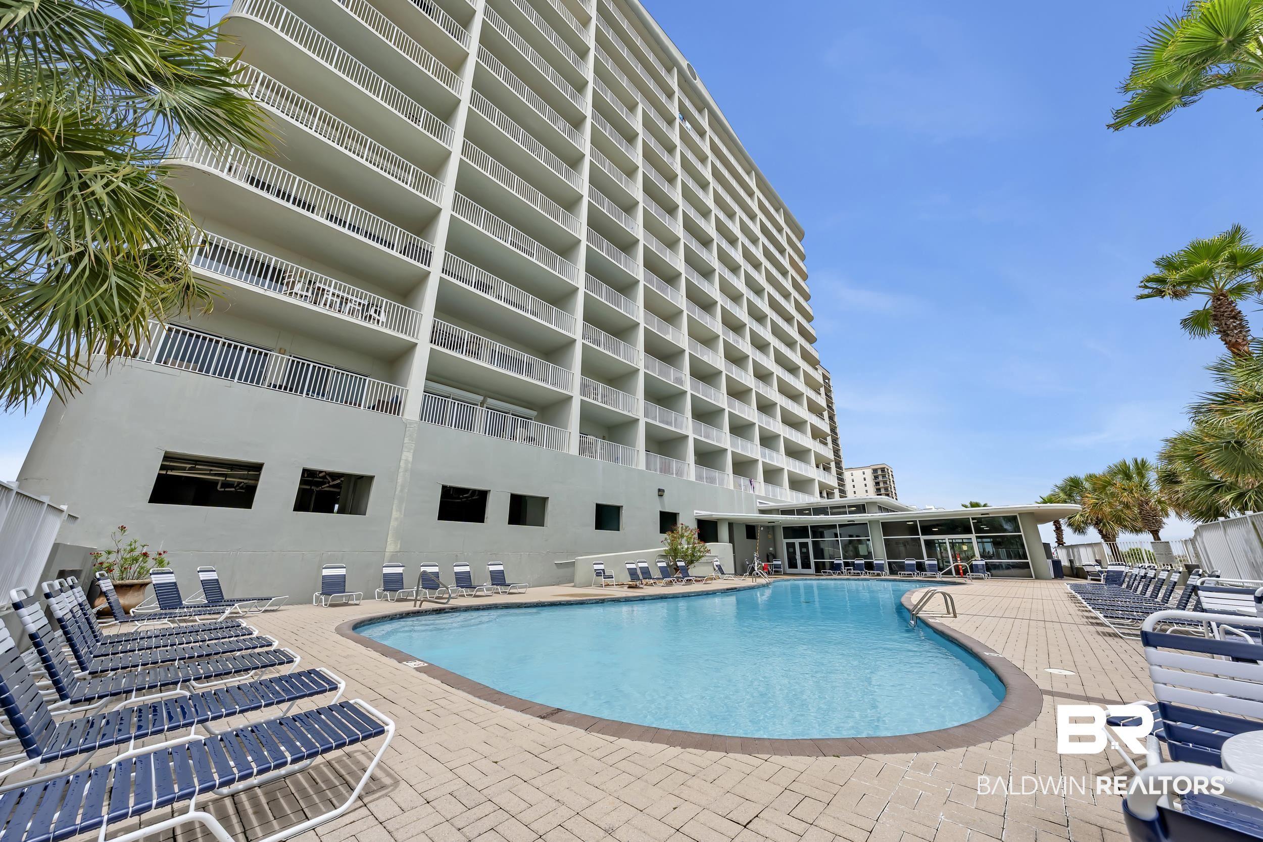 Image 2: Resort-style pool area featuring a curved swimming pool, surrounding paver patio, and multiple lounge chairs