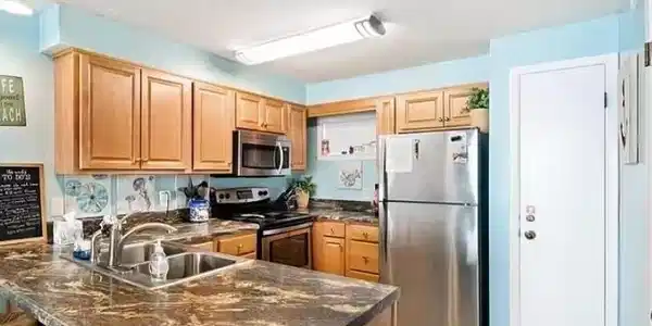 Image 4: Kitchen featuring stainless steel appliances, a kitchen breakfast bar, a peninsula, light tile patterned flooring, and dark stone countertops