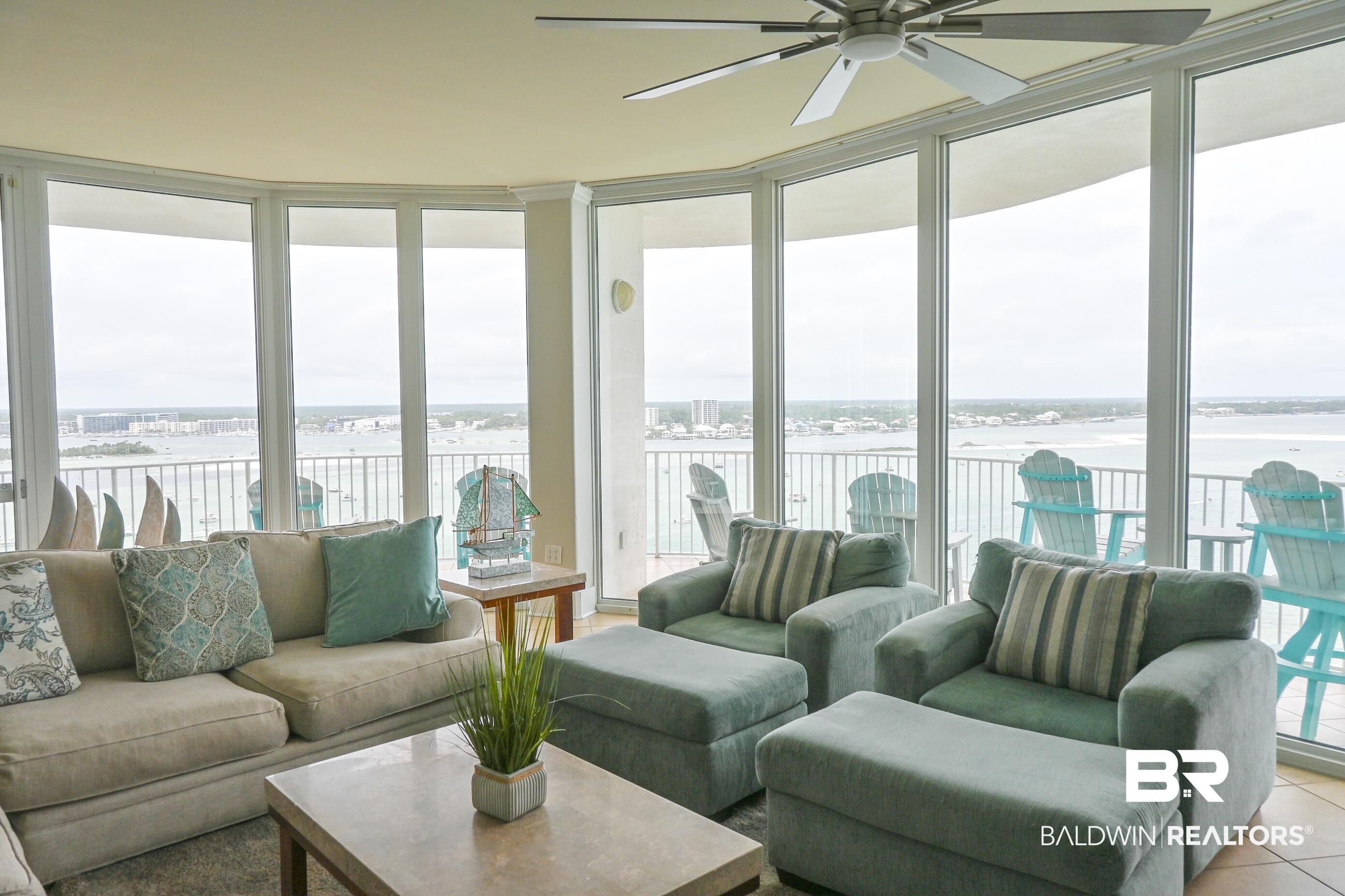 Image 3: Expansive living area with floor-to-ceiling windows, a ceiling fan, and access to an outdoor balcony