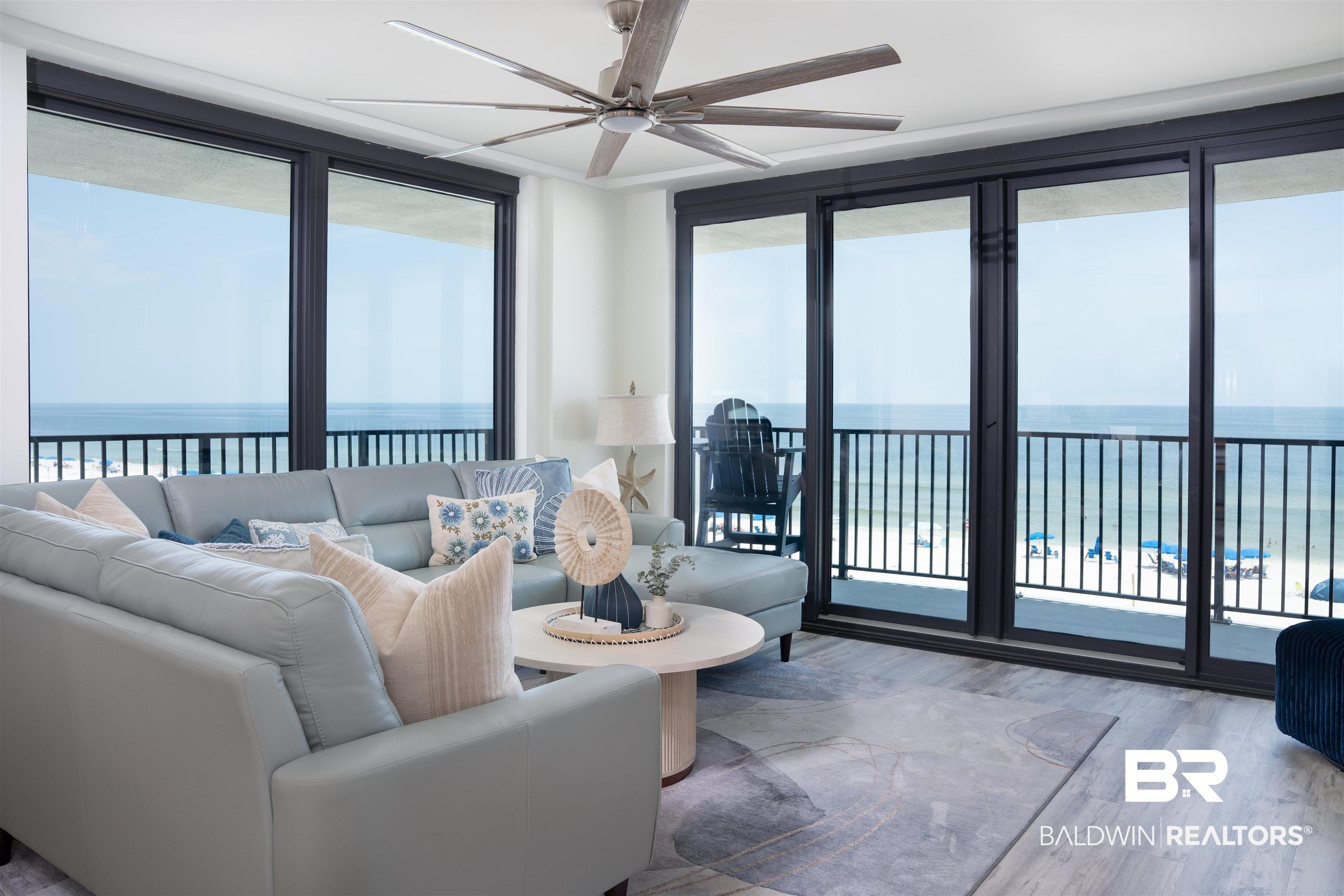Image 2: Living space featuring full-height sliding glass doors opening to a balcony with metal railings and expansive ocean scenery