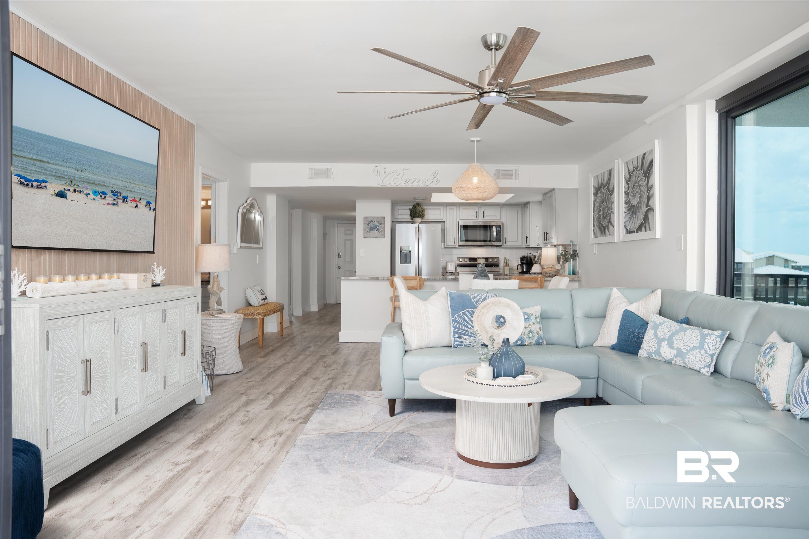 Image 4: Open-concept living space featuring wood-finish flooring, a contemporary ceiling fan, and large windows providing abundant natural light
