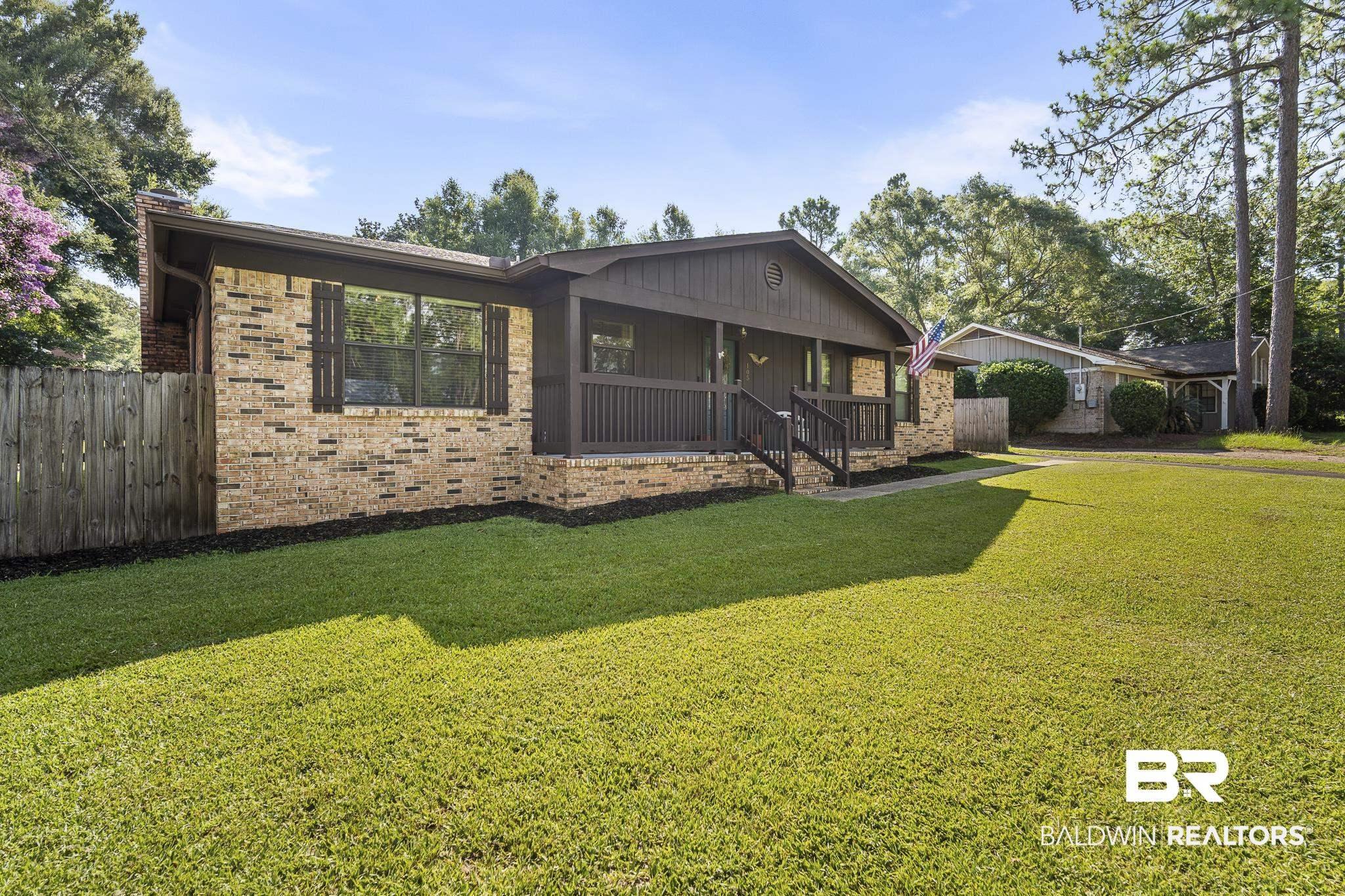 Image 2: Brick exterior featuring a covered front porch with dark wood railings and stairs