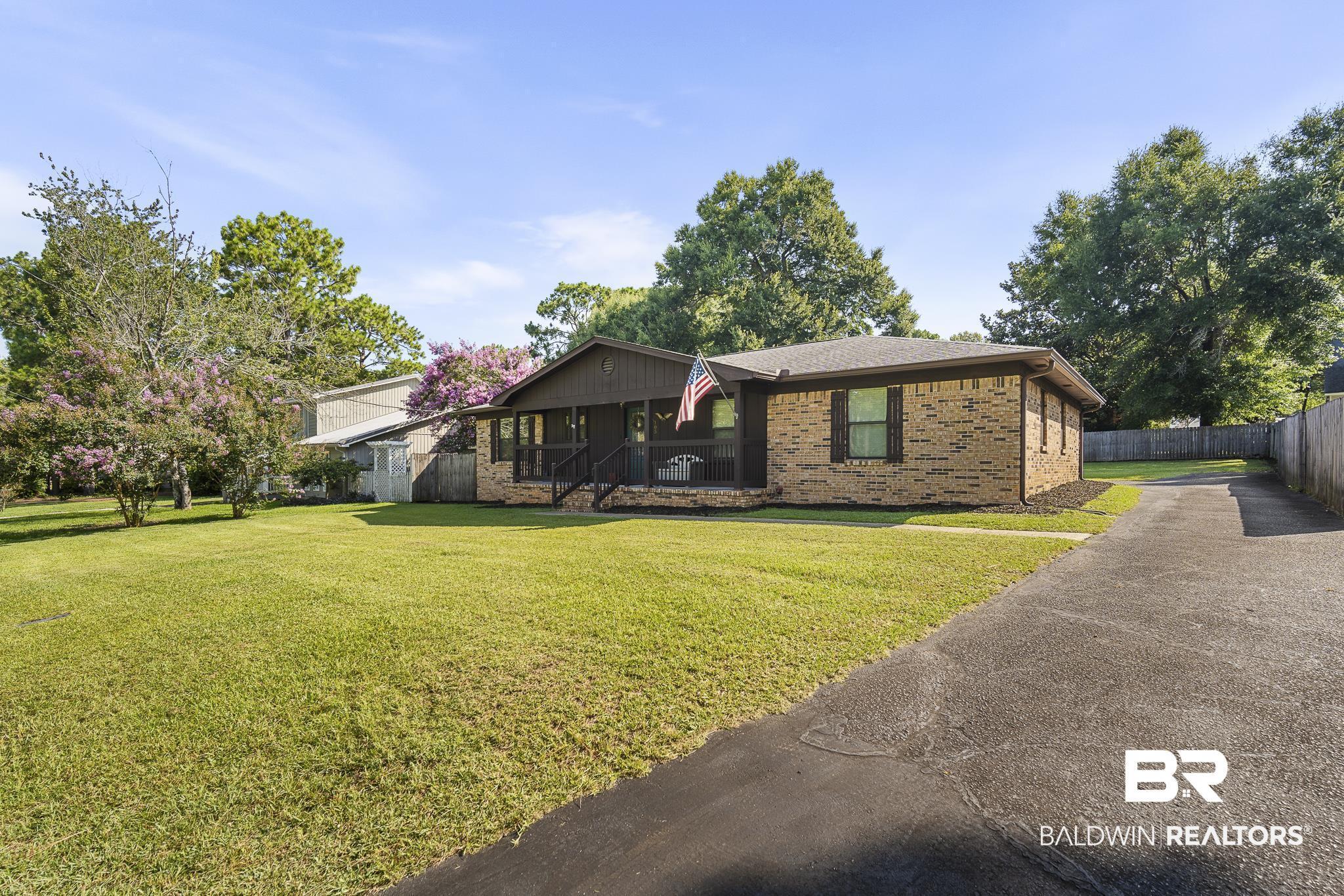 Image 3: Brick exterior with dark shutters, covered front porch, and mature landscaping