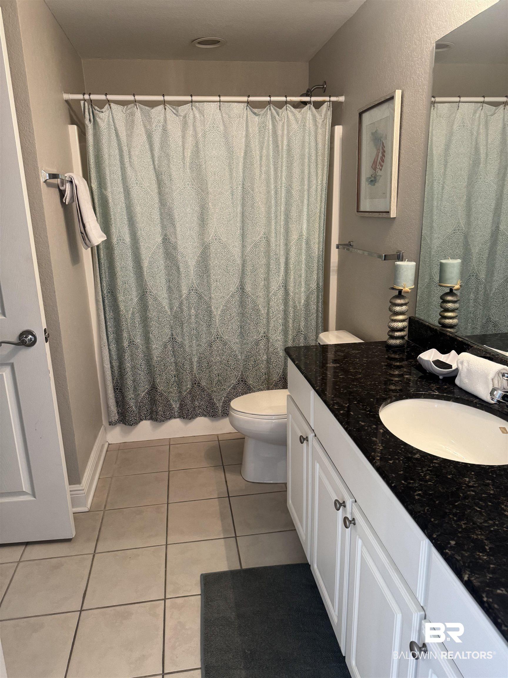 Image 3: Bathroom featuring light tile patterned floors, vanity, and a shower with curtain