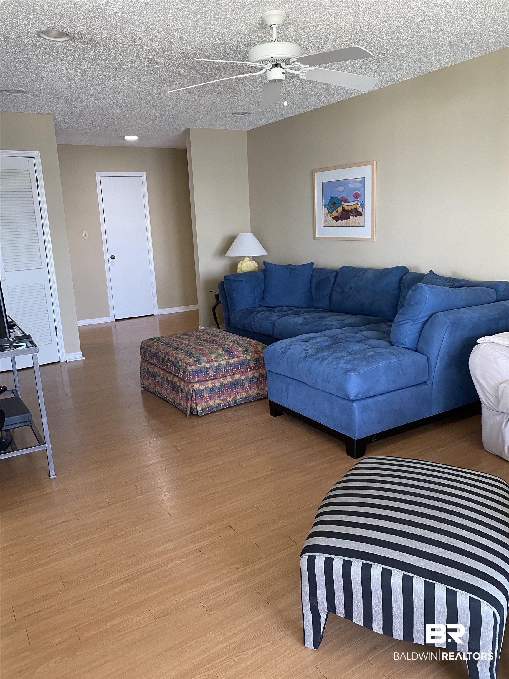 Image 4: Living room with a ceiling fan, light wood-style floors, and a textured ceiling