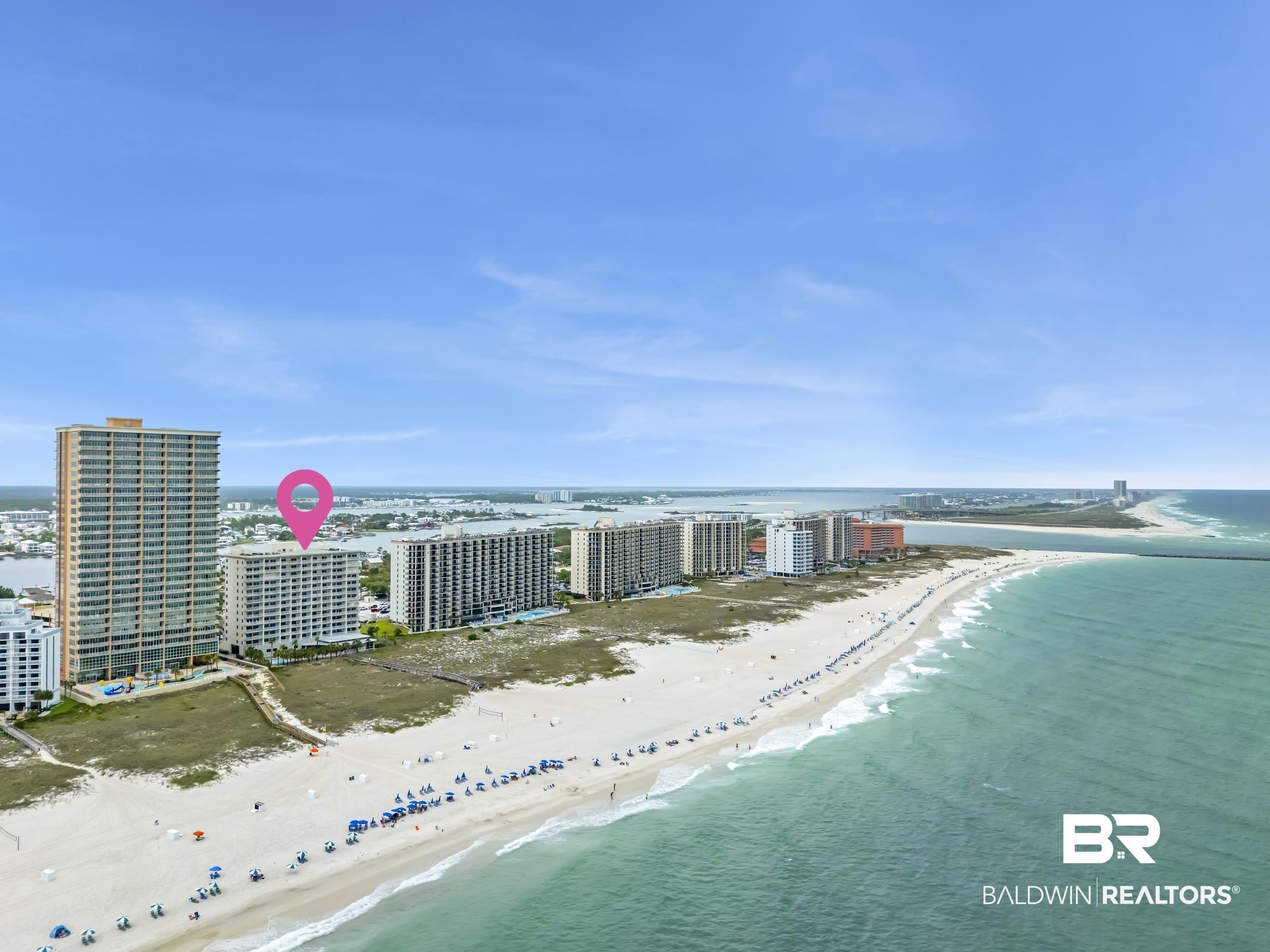Image 4: Beachfront high-rise building with extensive window lines, situated along a sandy coastline with clear water