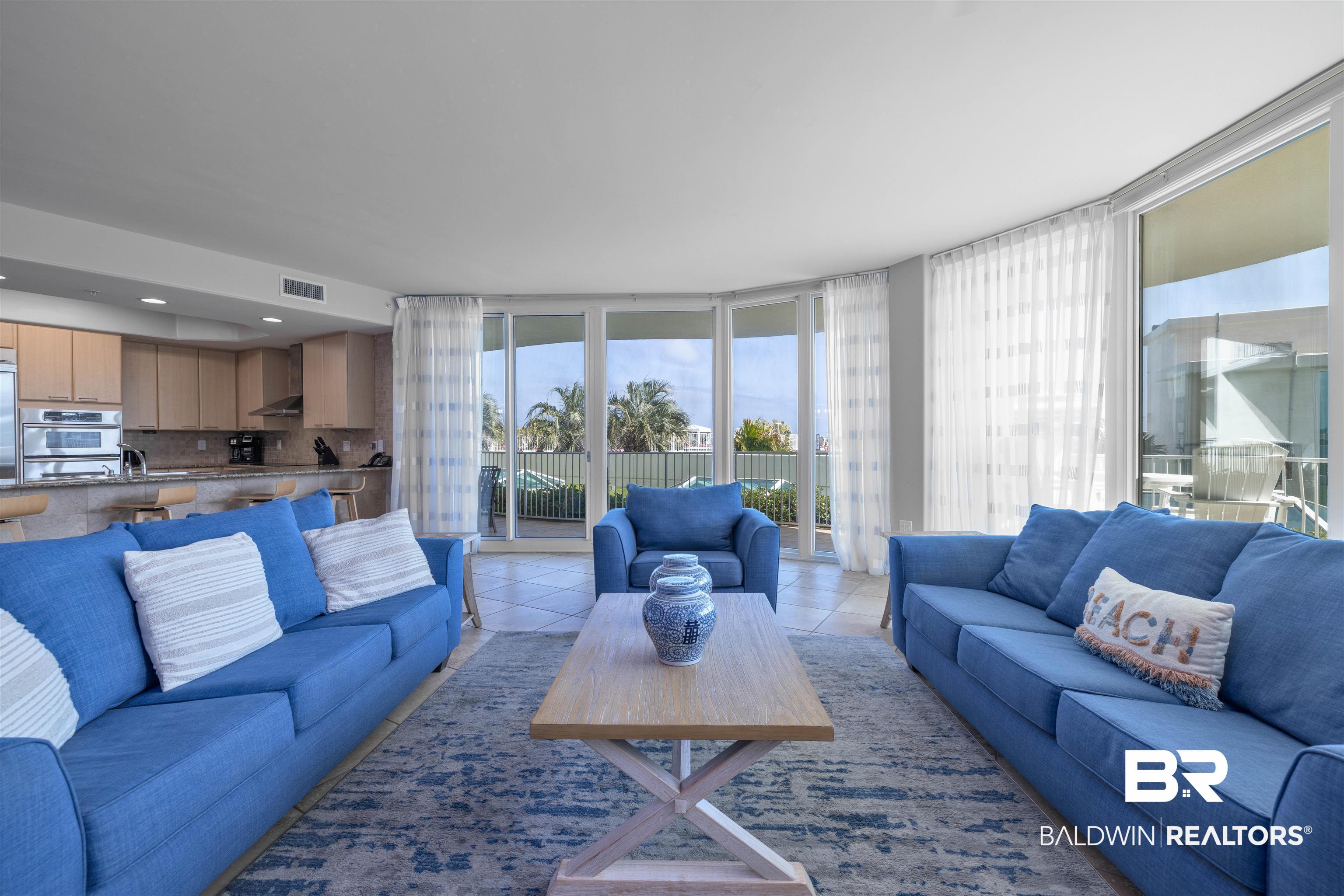 Image 2: Living room with healthy amount of natural light, light tile patterned floors, and floor to ceiling windows