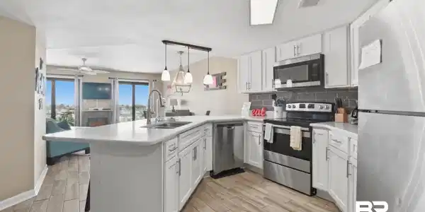 Image 2: Kitchen with stainless steel appliances, light countertops, white cabinets, and tasteful backsplash